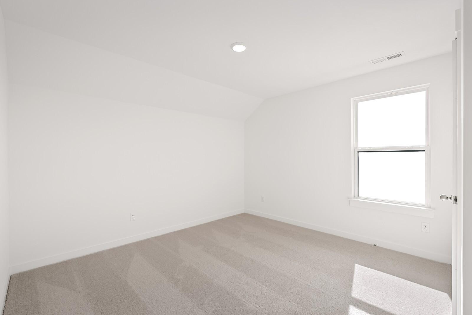 Bright secondary bedroom with sloped ceiling, large window, and light carpet in Davidson Homes The Ash C, Mt. Juliet, TN