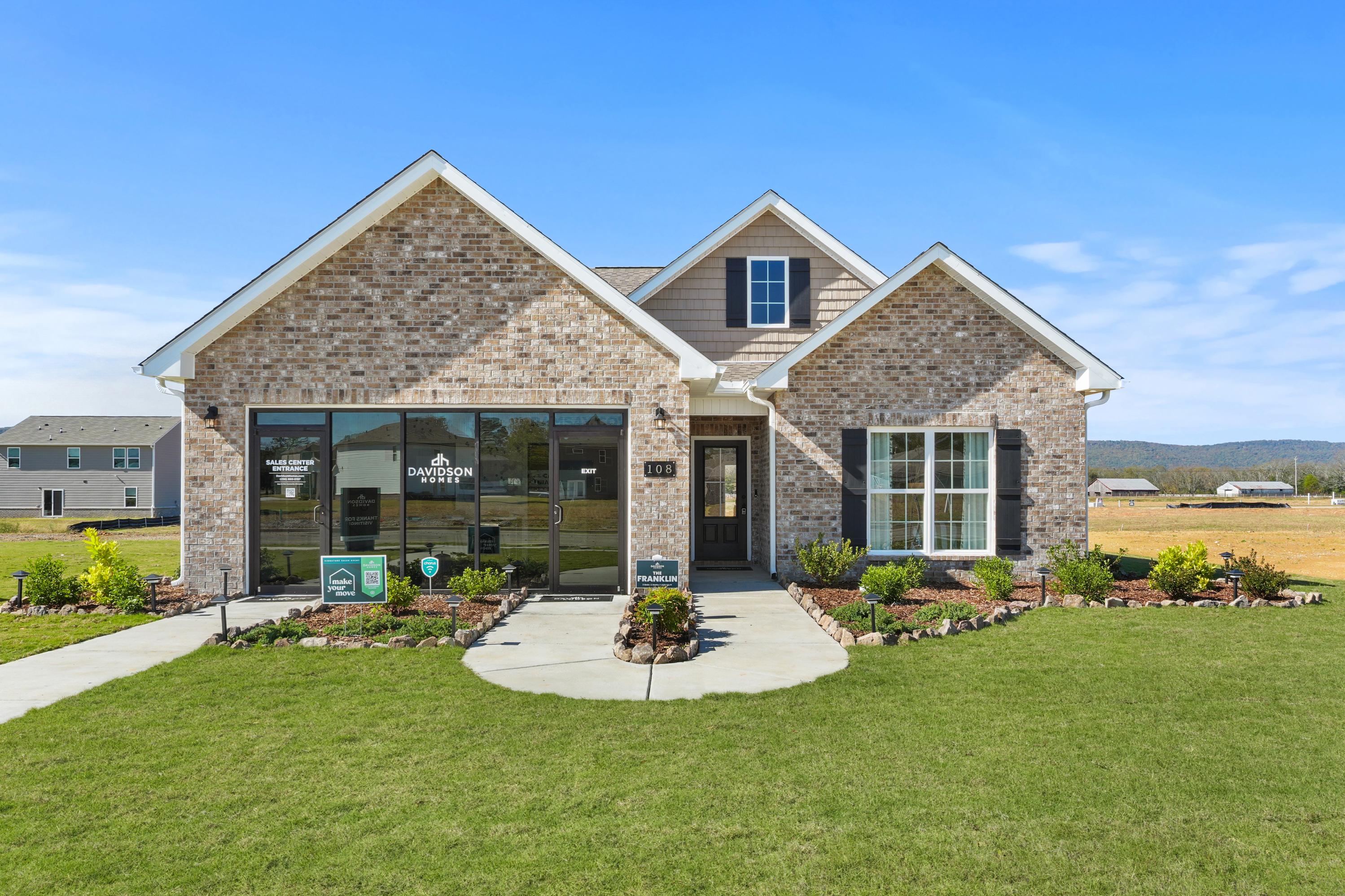 Davidson Homes model home exterior at Ramsay Cove in Owens Cross Roads AL with brick facade, large windows, and landscaped walkway