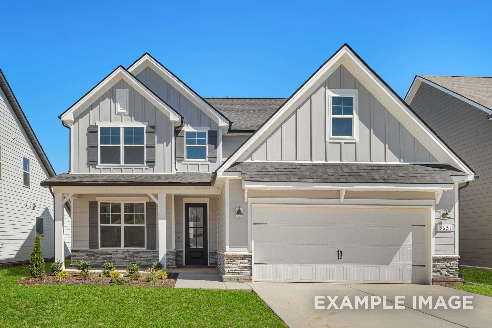 Two-story The Ash B home elevation by Davidson Homes: white board-and-batten siding, stone accents, covered porch, two-car garage, lush green lawn