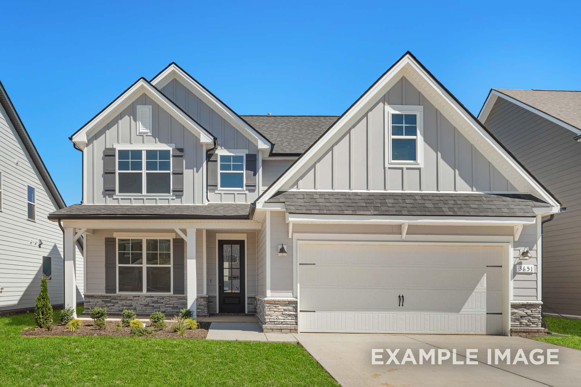 Two-story The Ash B home elevation by Davidson Homes: white board-and-batten siding, stone accents, covered porch, two-car garage, lush green lawn
