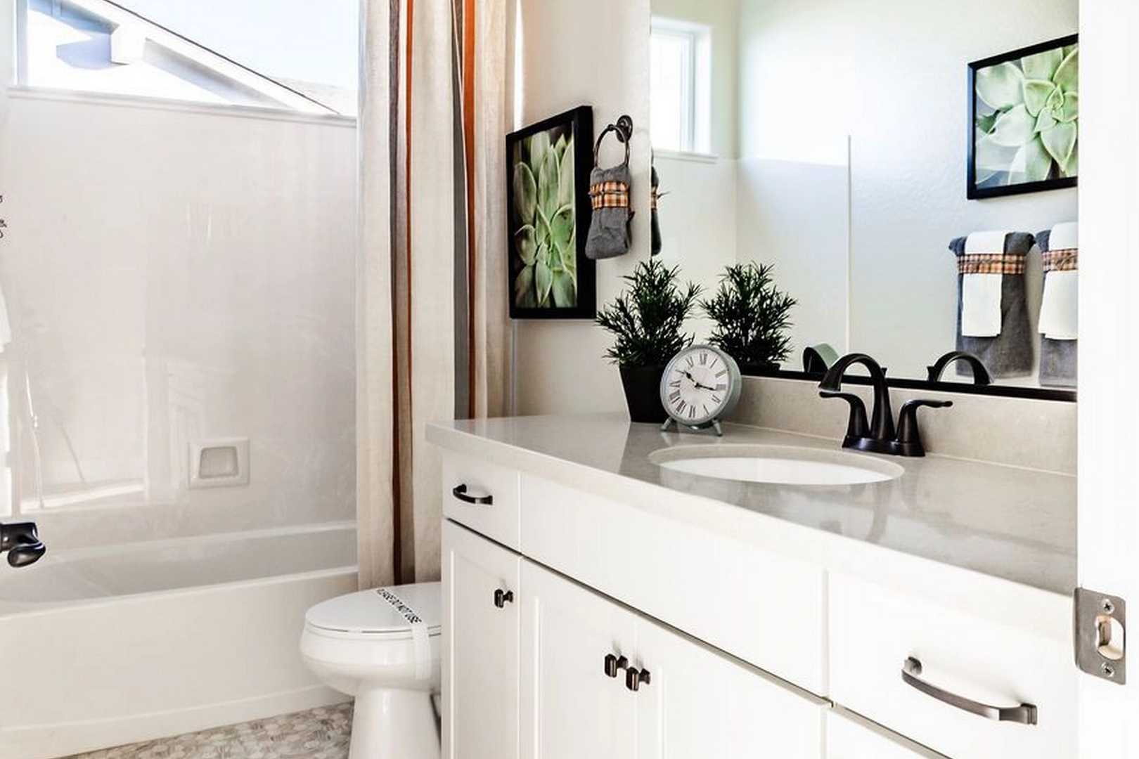 Modern bathroom in The Monarch by Evermore Homes with white subway tile, soaking tub, white vanity, and potted plants