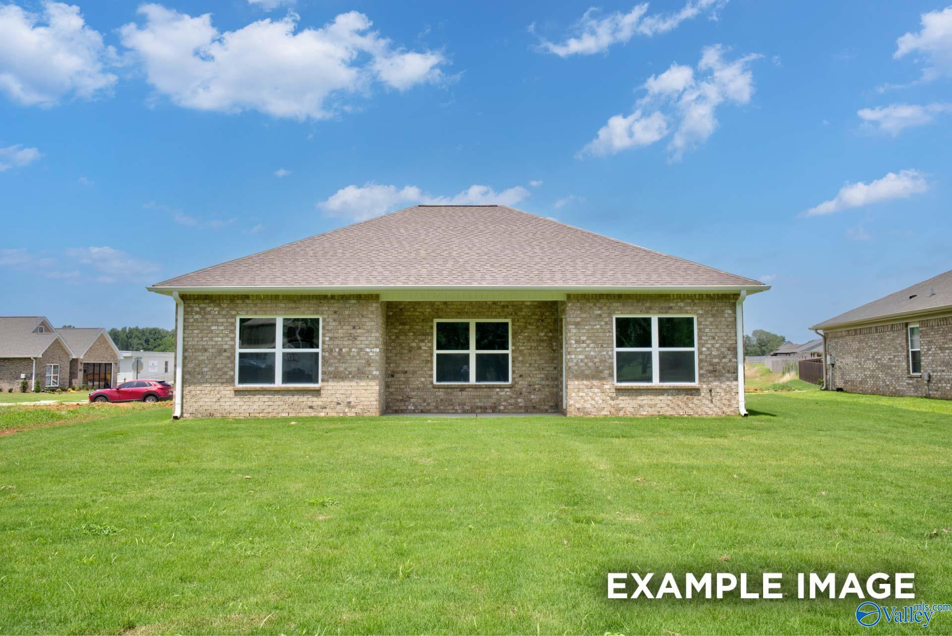 Brick single-story 3-bedroom home exterior with covered entry, large windows, and lush green lawn in Lynn Meadows, Meridianville, Alabama
