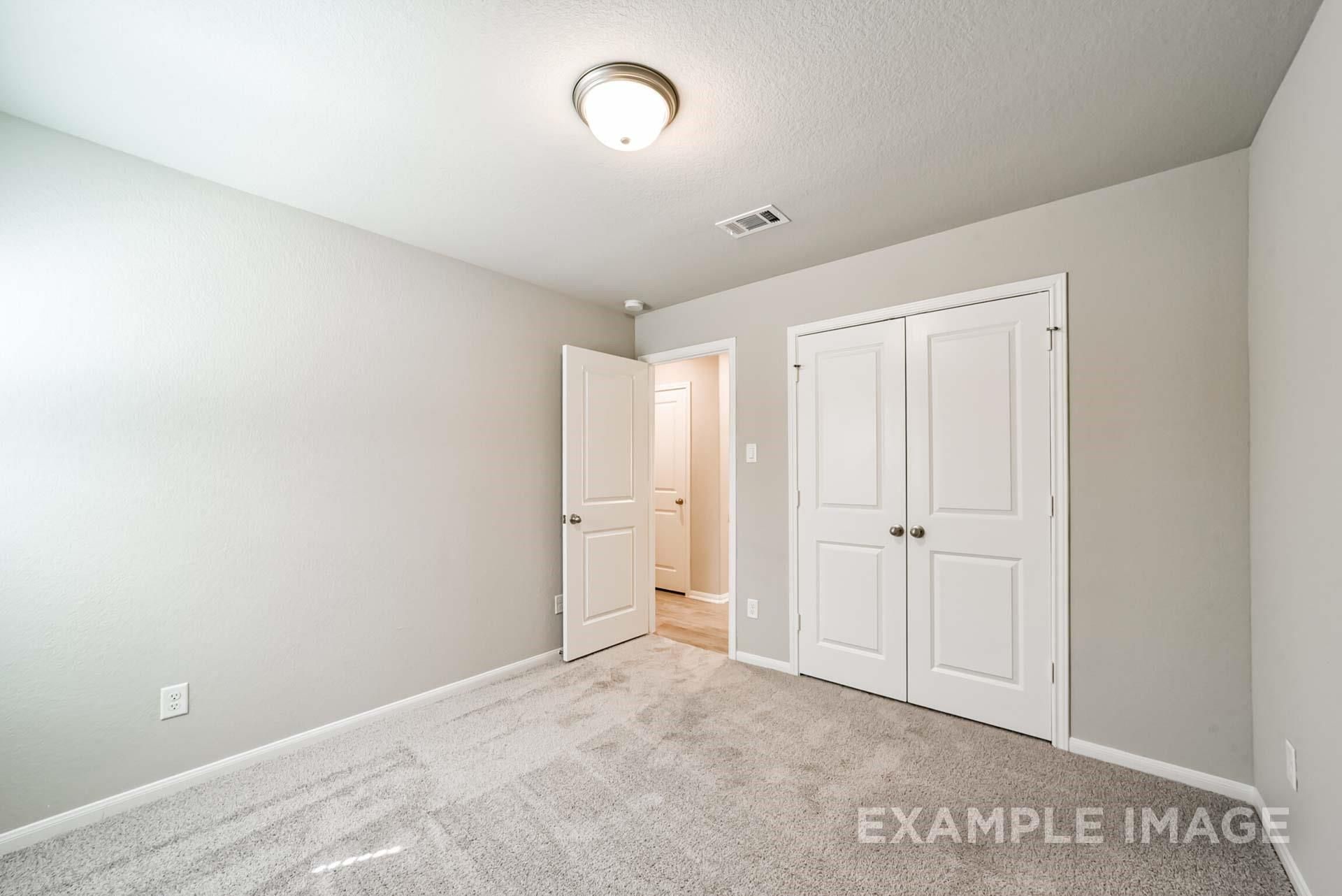 Bright secondary bedroom with plush carpet and closet in The Riviera A floor plan at Emberly, Beasley, Texas.