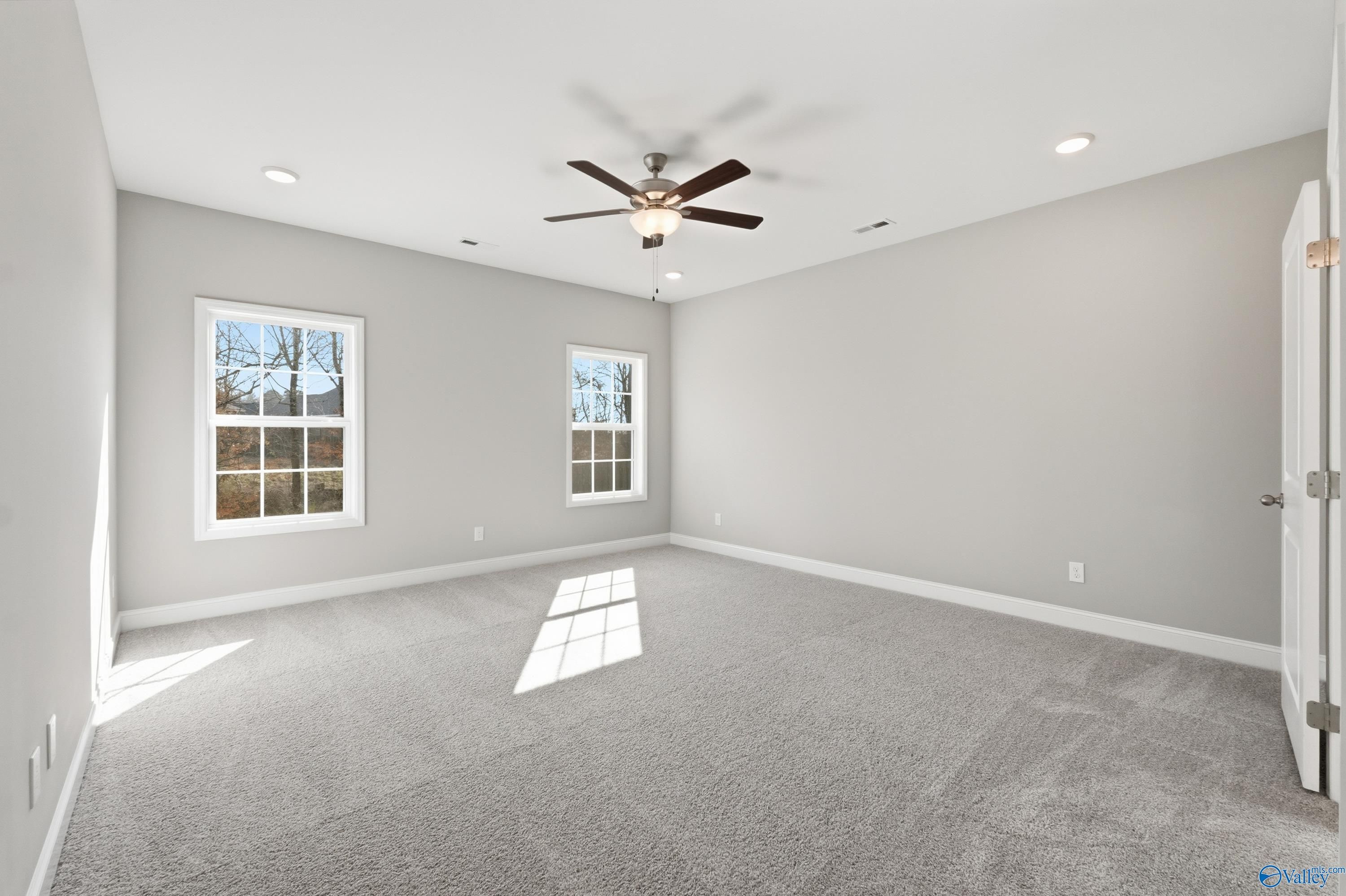 Bright secondary bedroom with gray walls, beige carpet, ceiling fan, and large sunny windows in Davidson Homes The Rockford, Harvest, Alabama