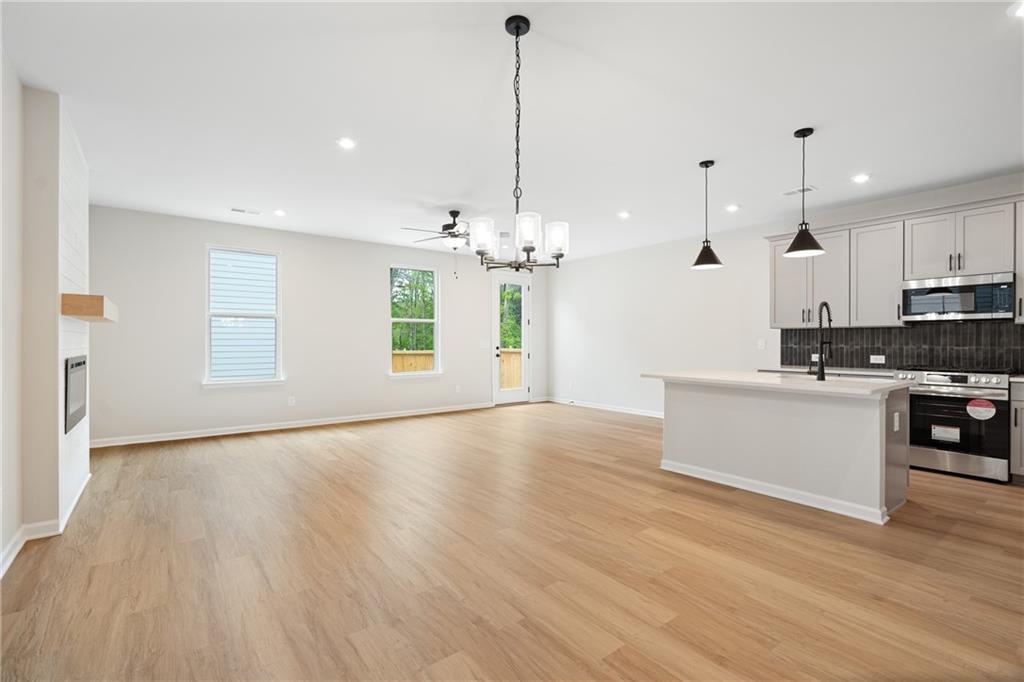 Open-concept kitchen and living area with hardwood floors, white cabinets, stainless steel appliances, chandelier, and fireplace in The Marion A floor plan, Kennesaw, GA