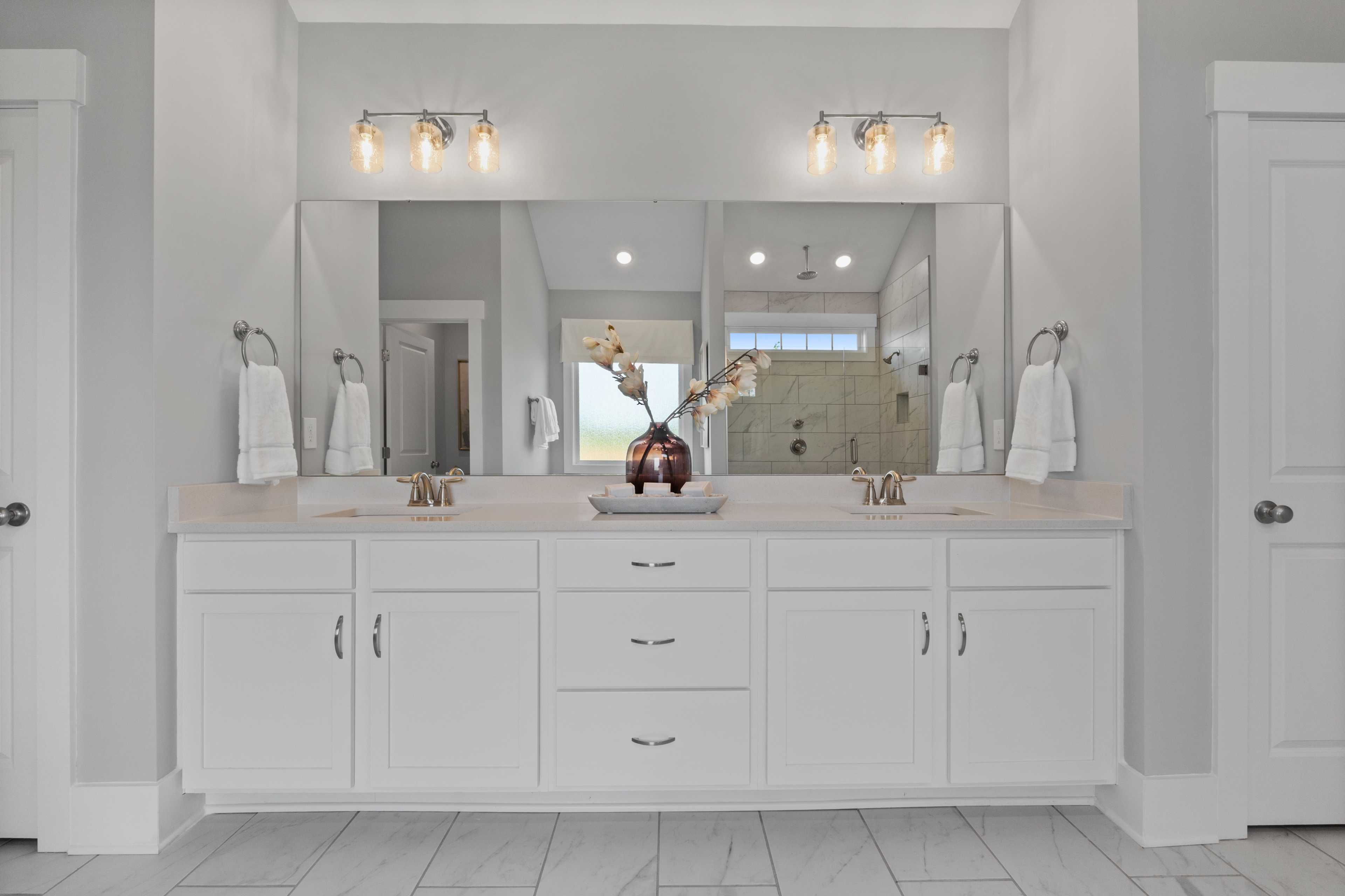 Spacious double vanity bathroom at Creekside in Harvest AL with white cabinets, gray walls, mirrors, and walk-in shower