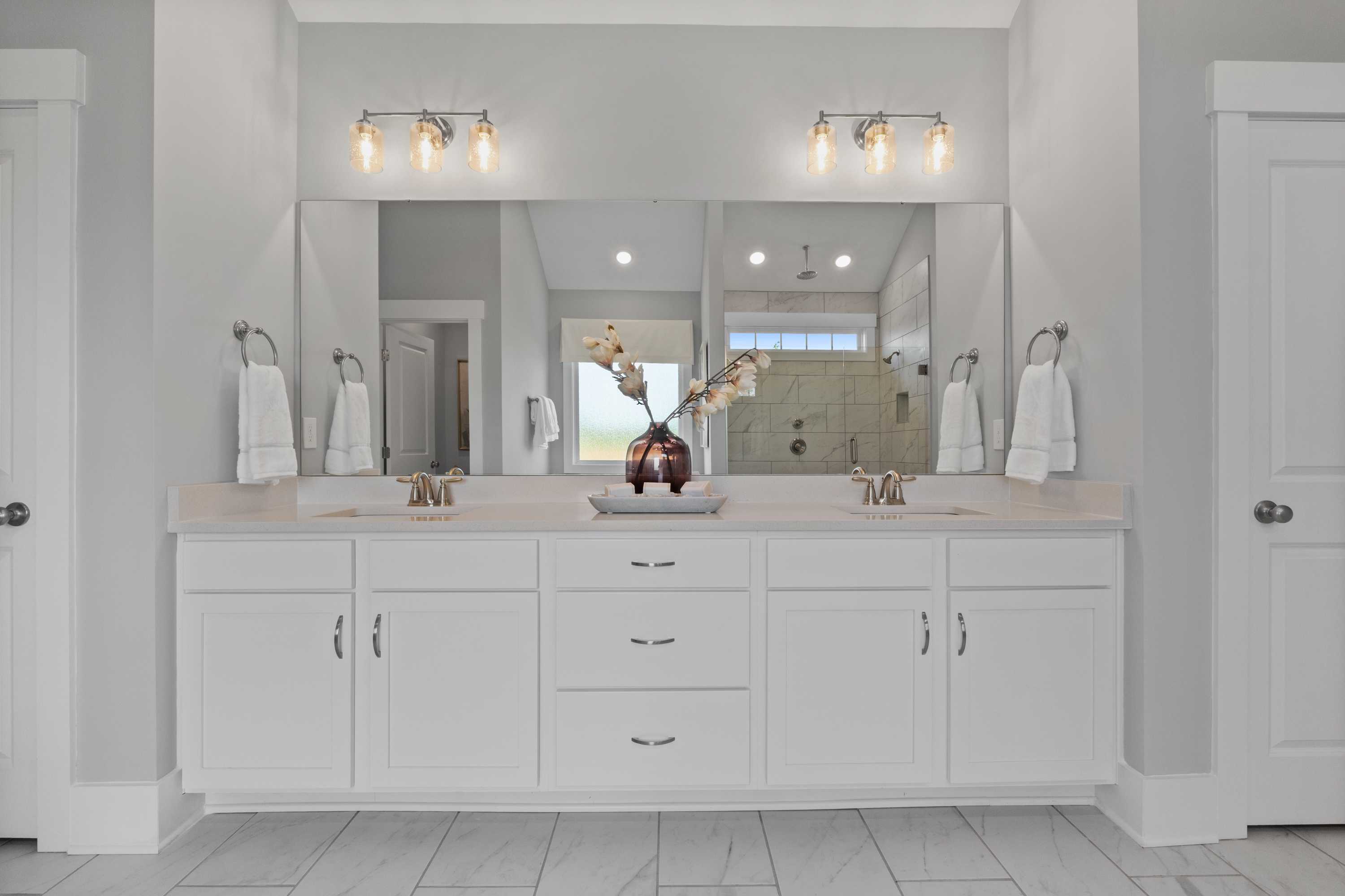 Spacious double vanity bathroom at Creekside in Harvest AL with white cabinets, gray walls, mirrors, and walk-in shower