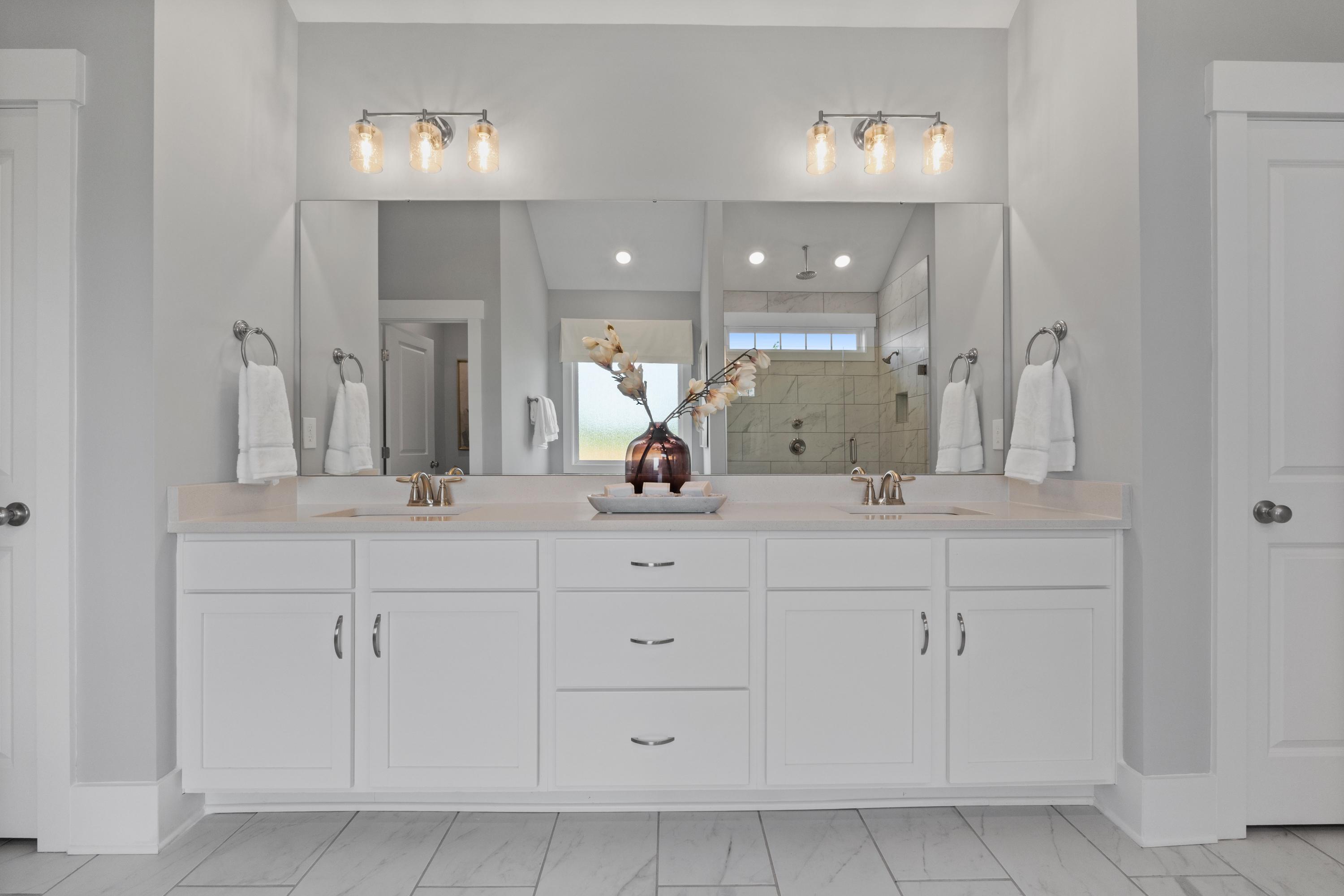 Spacious double vanity bathroom at Creekside in Harvest AL with white cabinets, gray walls, mirrors, and walk-in shower