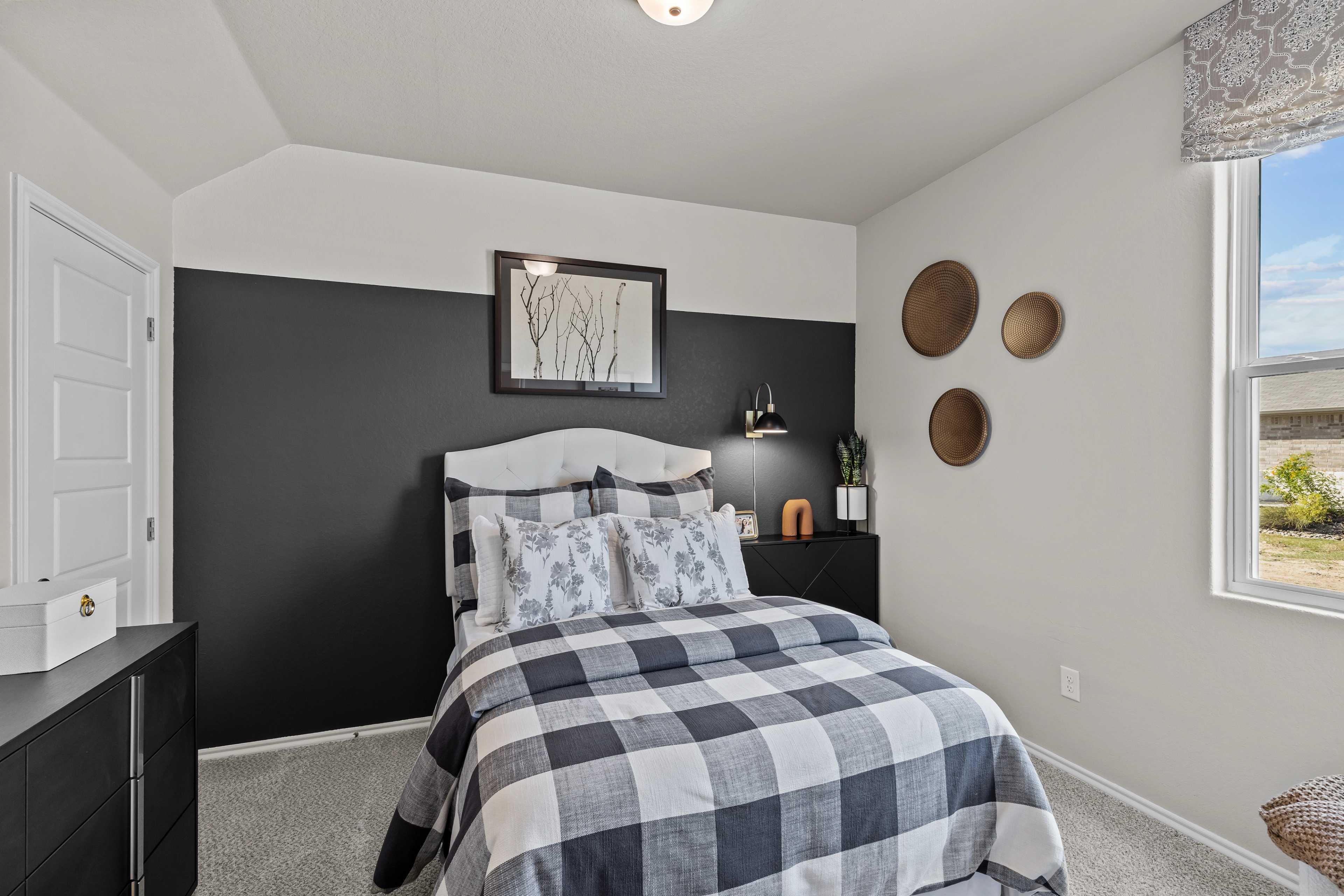 Cozy bedroom with black accent wall, checkered bedding and woven decor at Applewhite Meadows in San Antonio Texas