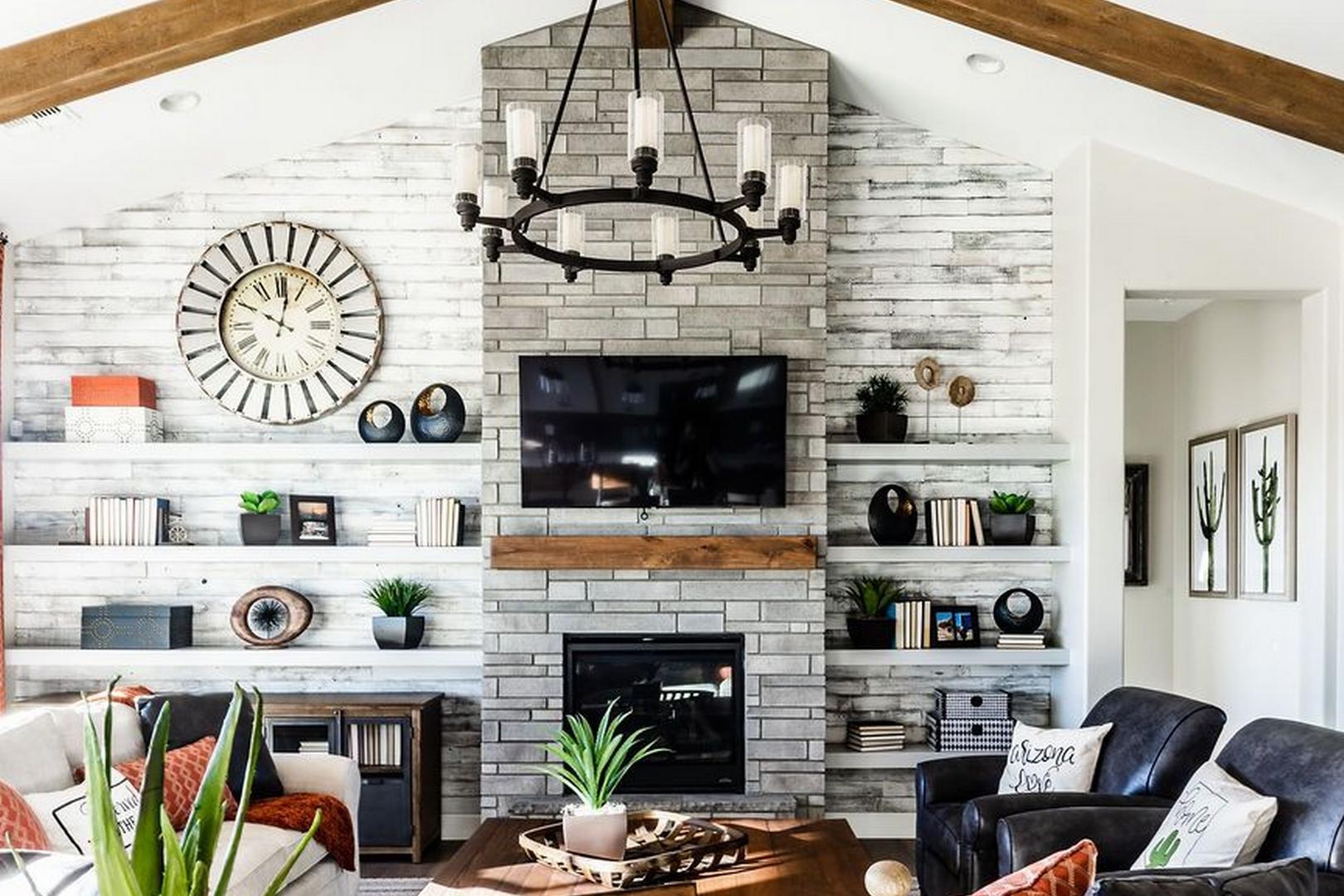 Spacious living room in The Monarch B showcasing rustic stone fireplace, vaulted wooden beams, leather chairs, and built-in shelves