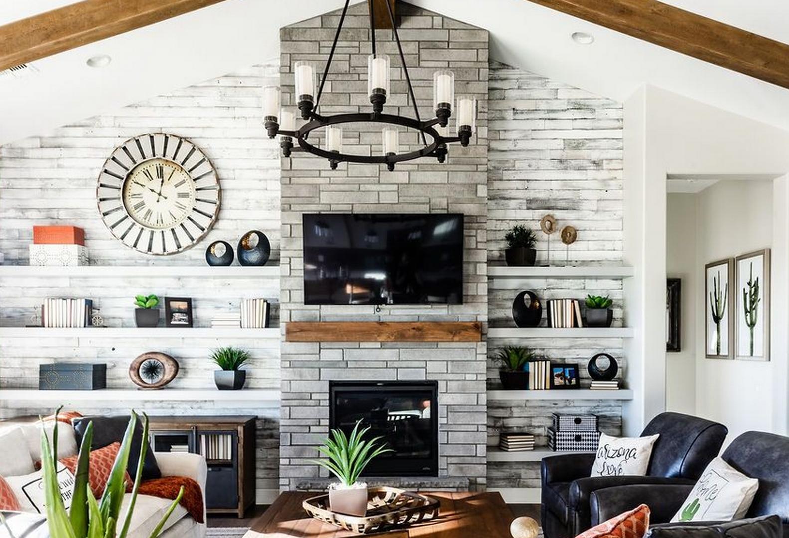 Cozy living room in The Monarch by Evermore Homes featuring stone fireplace, mounted TV, wooden chandelier, and leather seating