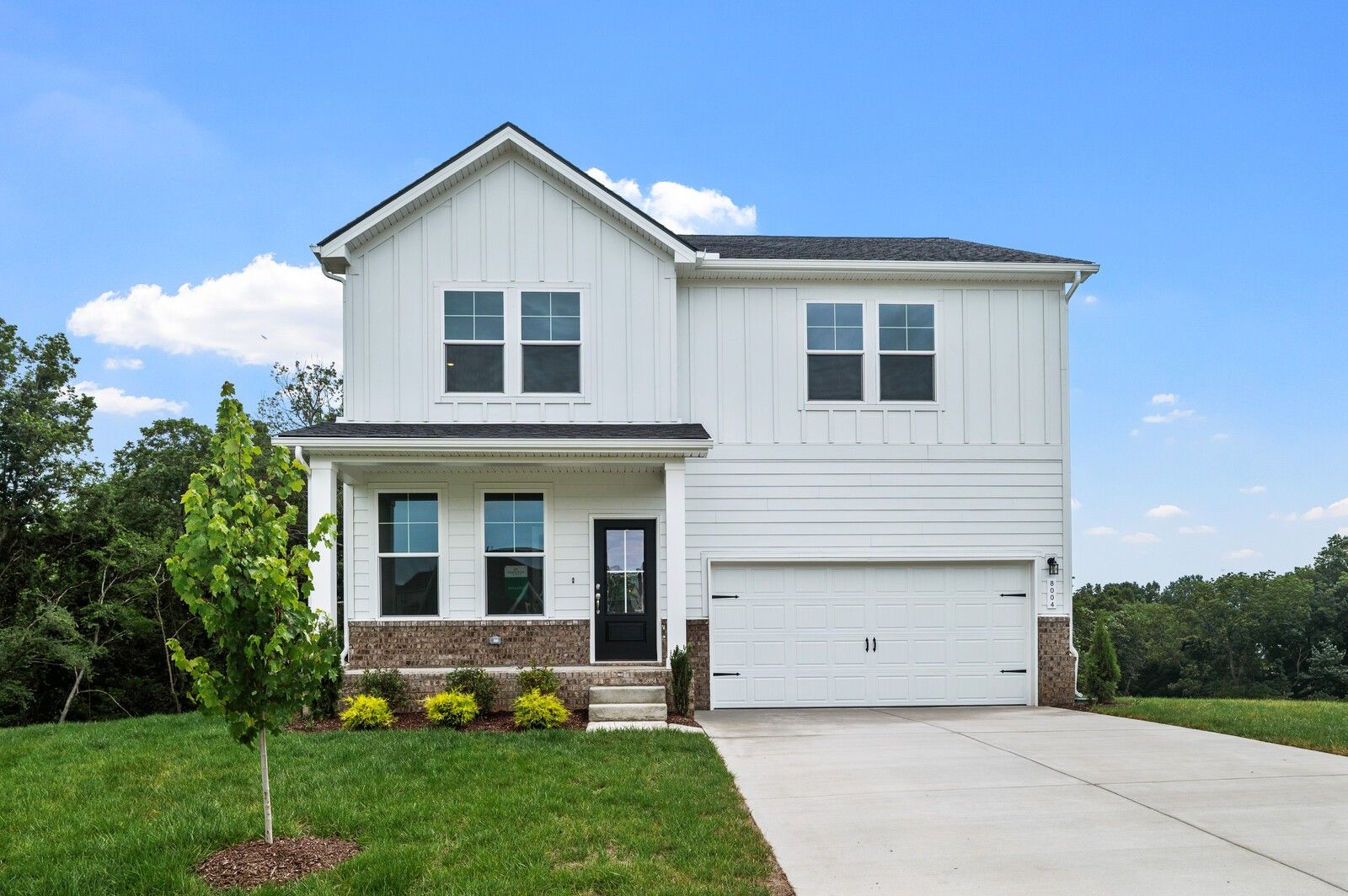 Two-story white farmhouse exterior with brick accents and 2-car garage, The Logan C plan in Calista Farms, White House, TN.