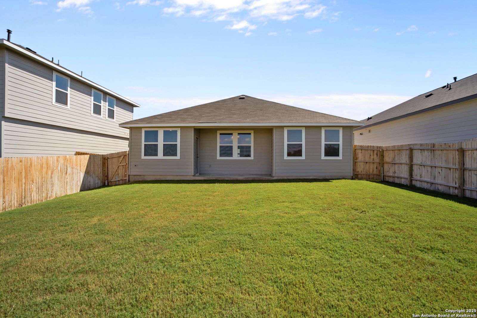 Private backyard with lush green lawn, wooden privacy fence, and covered patio in Davidson Homes The Asheville H, Horizon Pointe, Converse, Texas