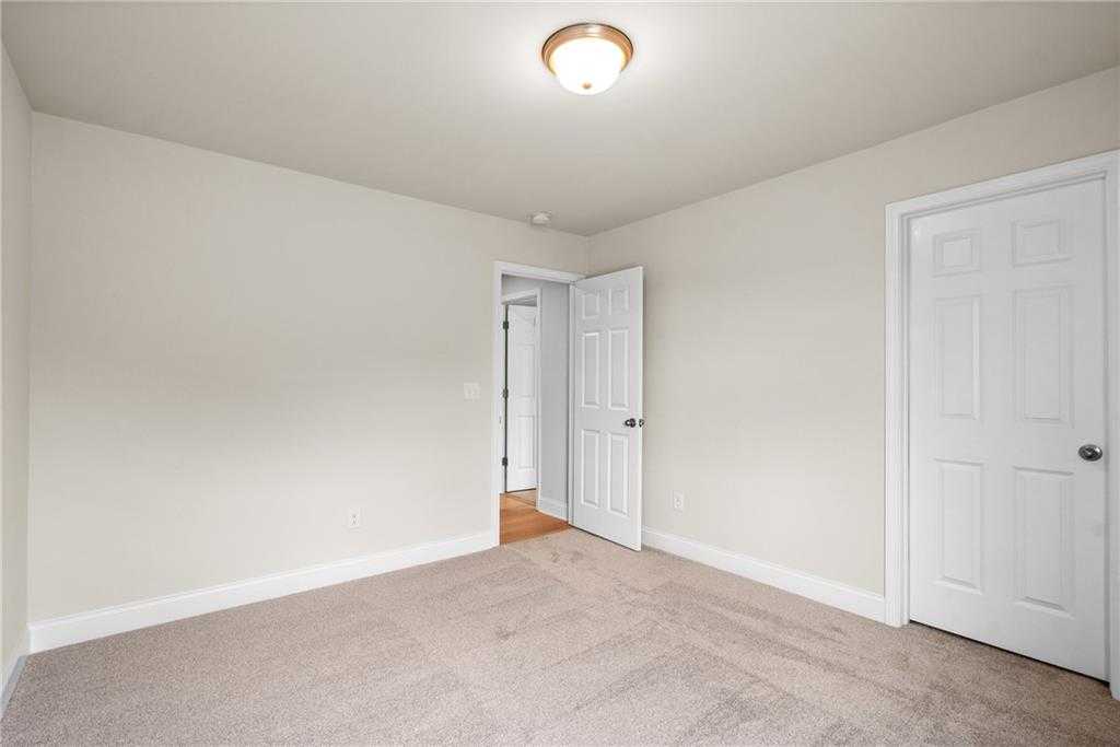 Spacious secondary bedroom with beige walls, neutral carpet, and white doors in Davidson Homes The Hickory B, Hoschton GA