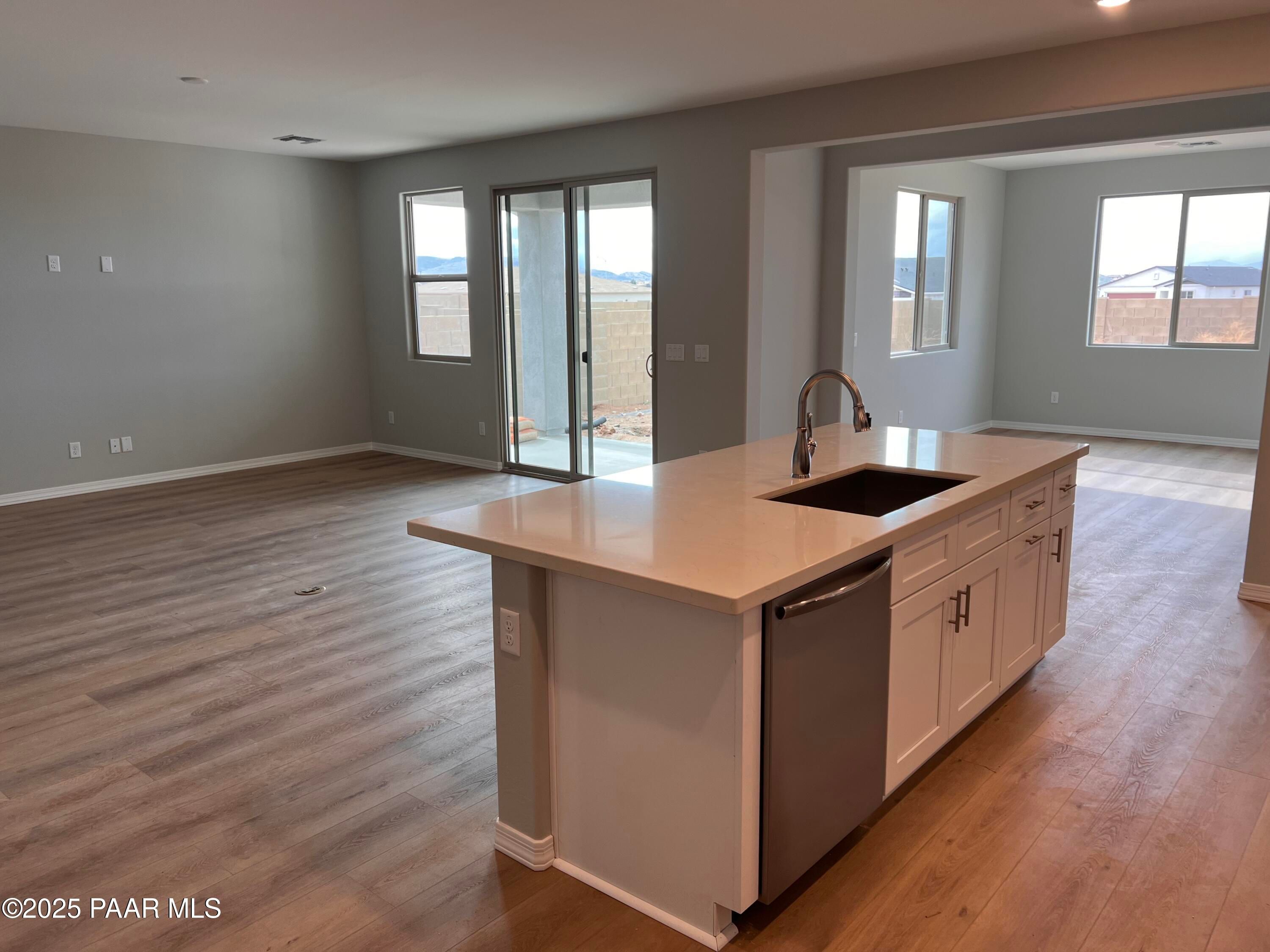 Open-concept kitchen island with stainless sink and dishwasher, sliding doors to patio in Davidson Homes Inspiration B, Prescott Valley, AZ
