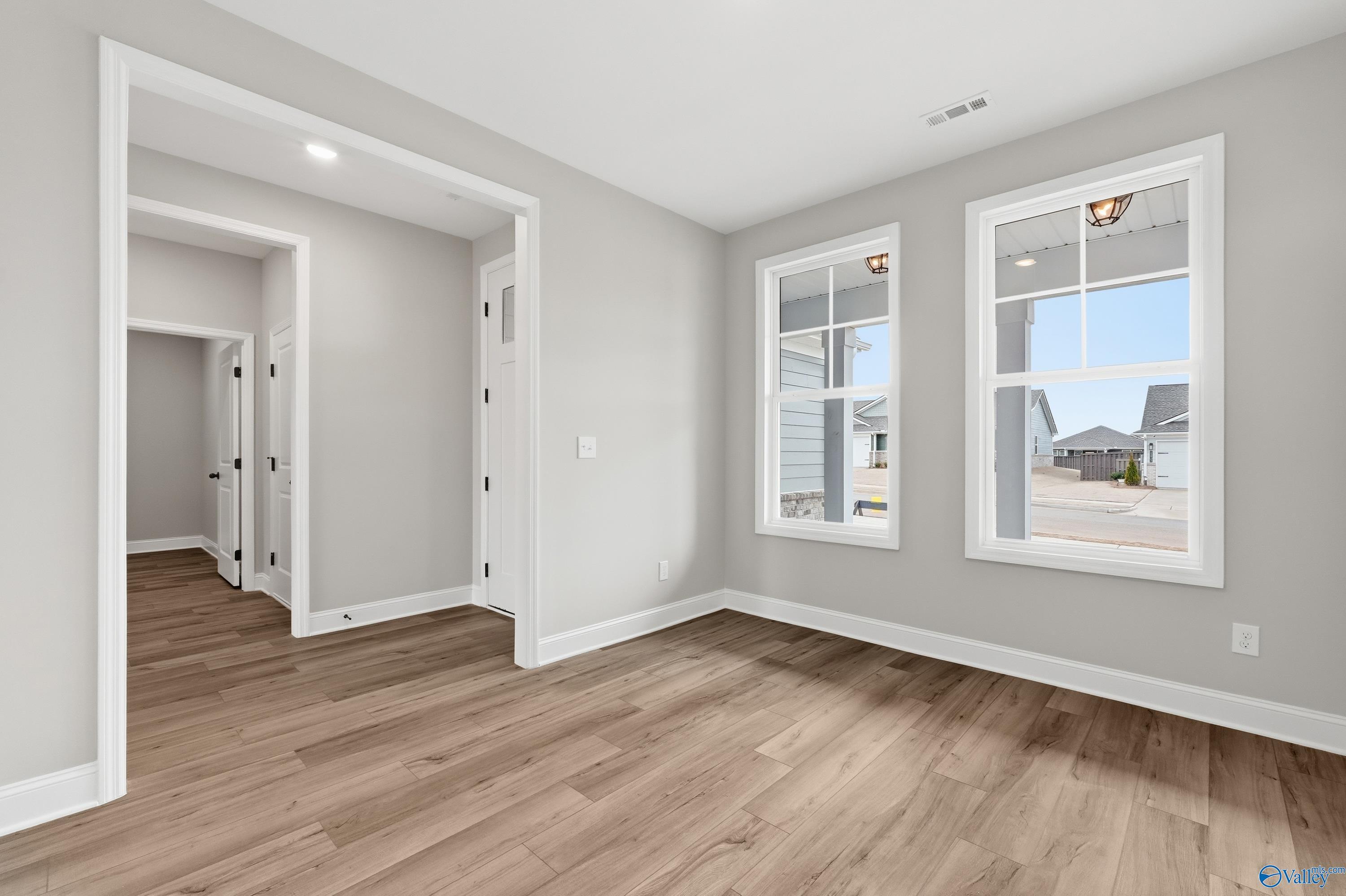 Bright living room with hardwood floors, gray walls, and large windows in Davidson Homes The Rockford C, Athens Alabama