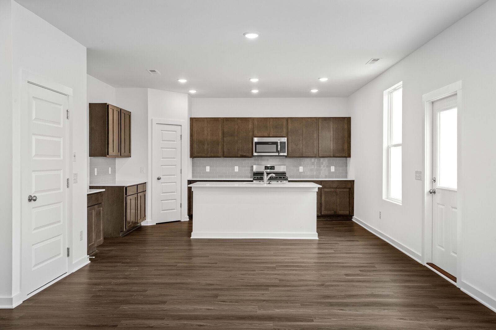Spacious modern kitchen with white island, shaker cabinets, and stainless appliances in Davidson Homes The Logan C, White House, TN