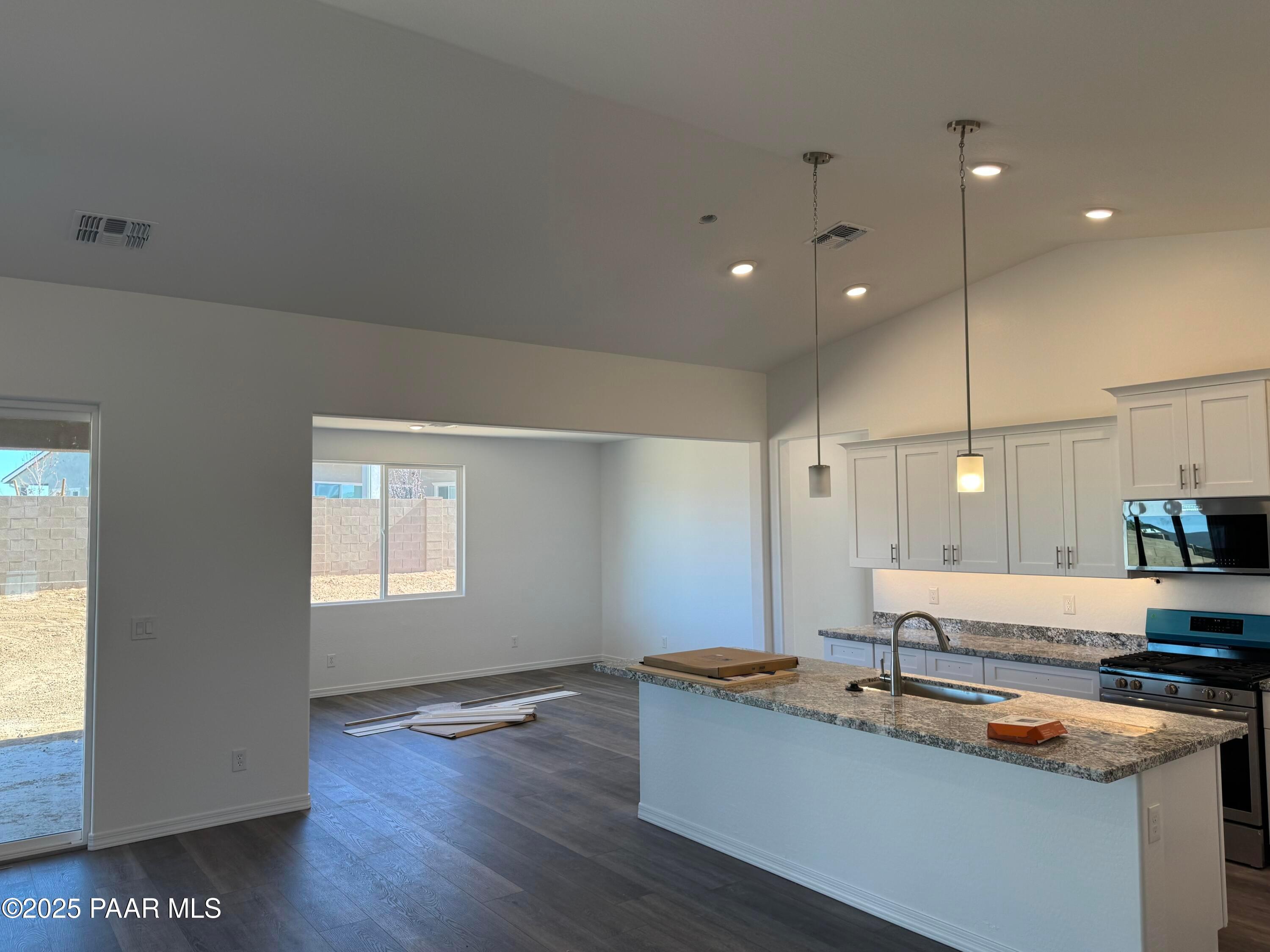 Modern open kitchen with white island, granite counters, stainless appliances in Davidson Homes Sunrise II A, Prescott AZ