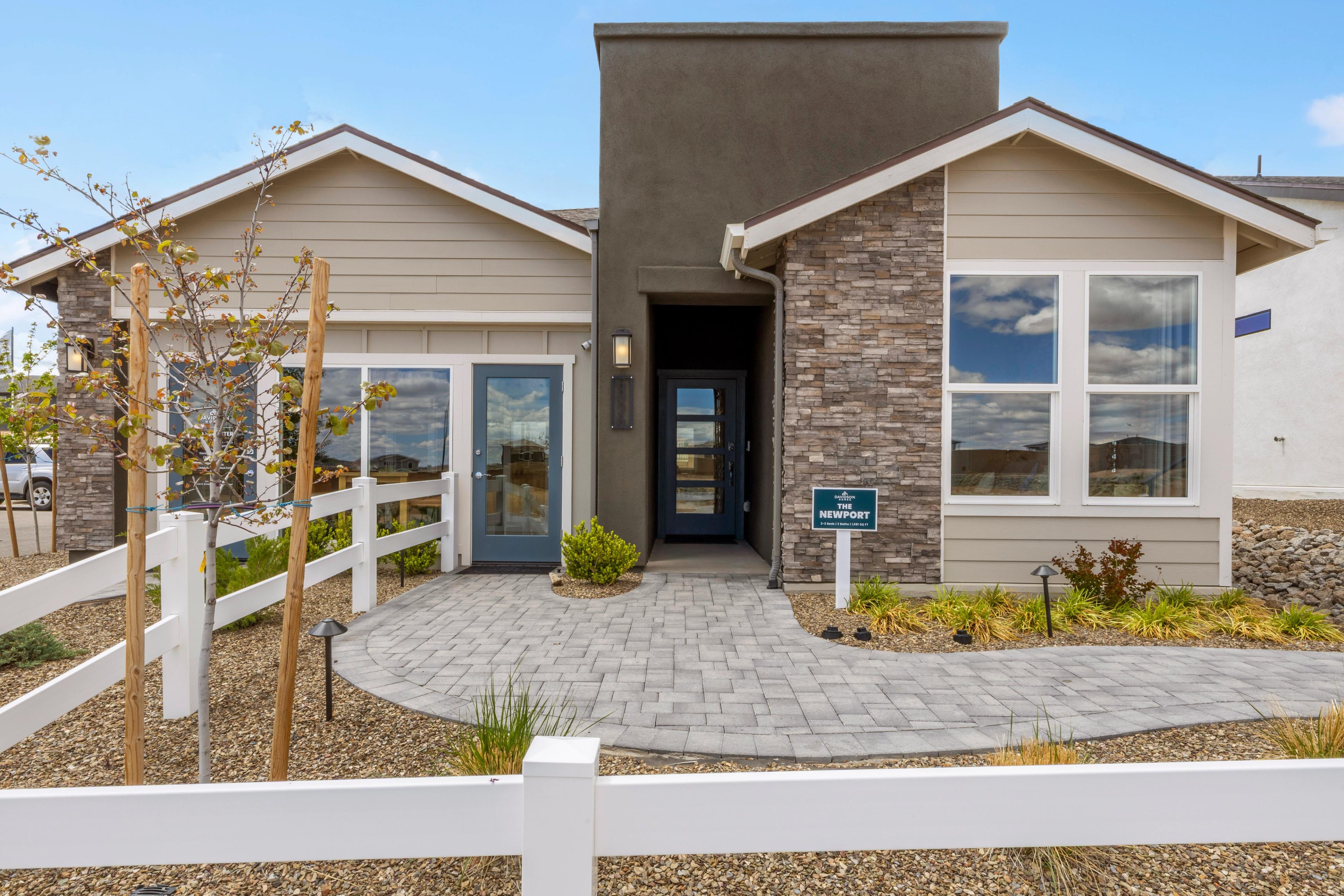 Newport model home exterior at South Ranch in Prescott AZ with stone facade, paver walkway and white fence