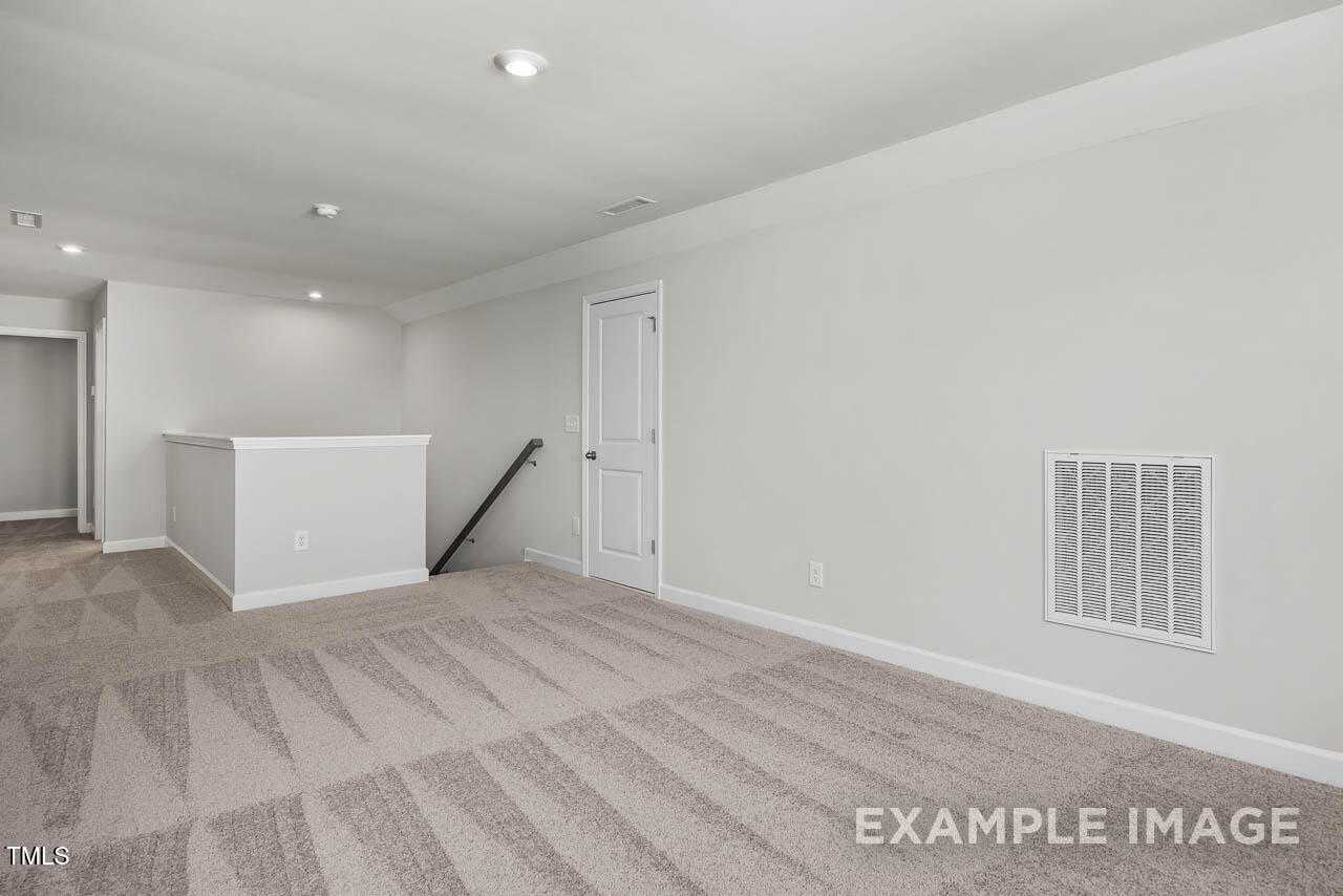 Spacious upstairs loft with beige carpet, white railing, recessed lights in 4-bed The Hickory II B home, Lillington, NC