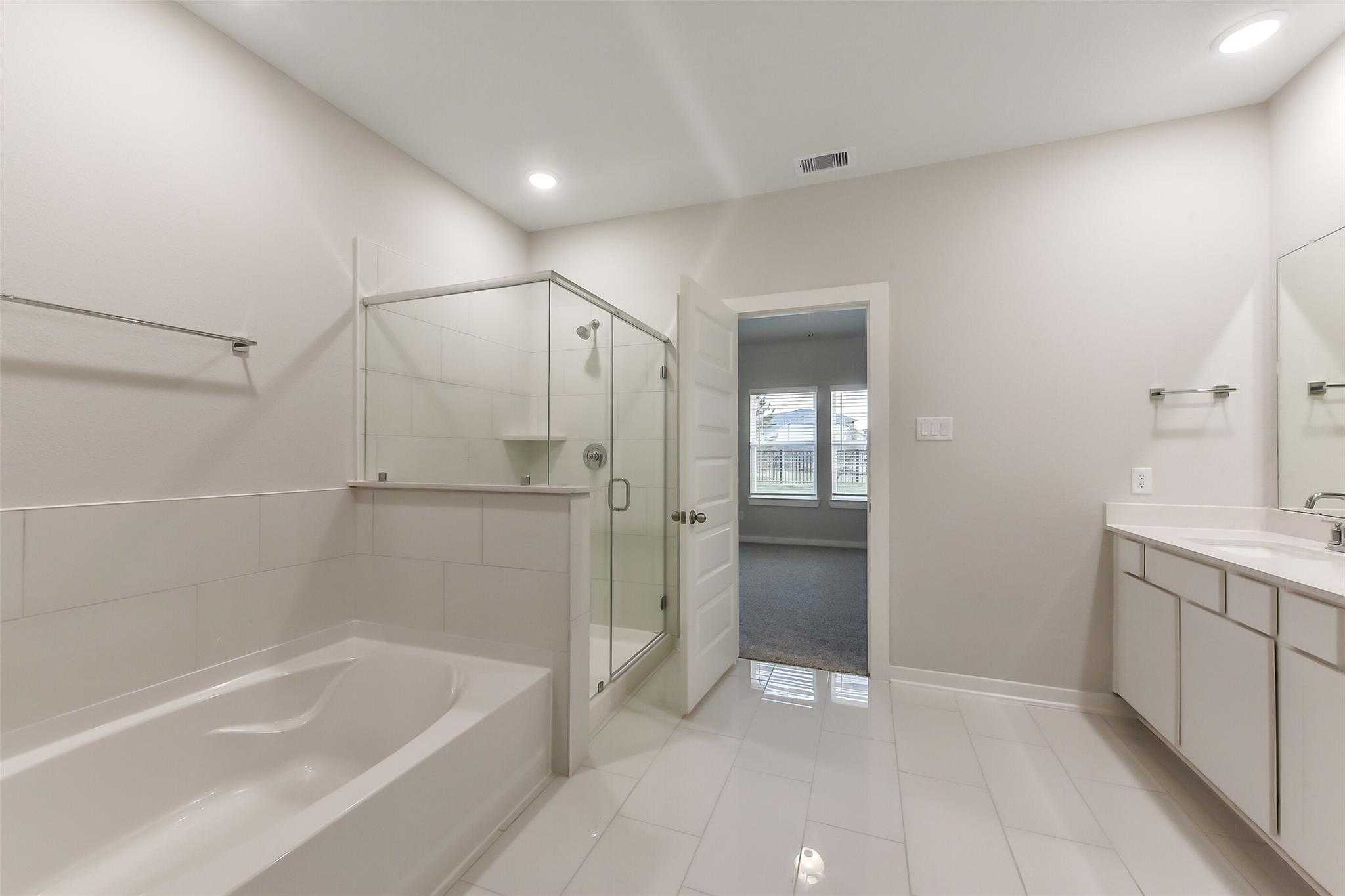 Modern master bathroom with freestanding tub, glass shower, double vanity in Davidson Homes The Laguna B, Katy, Texas