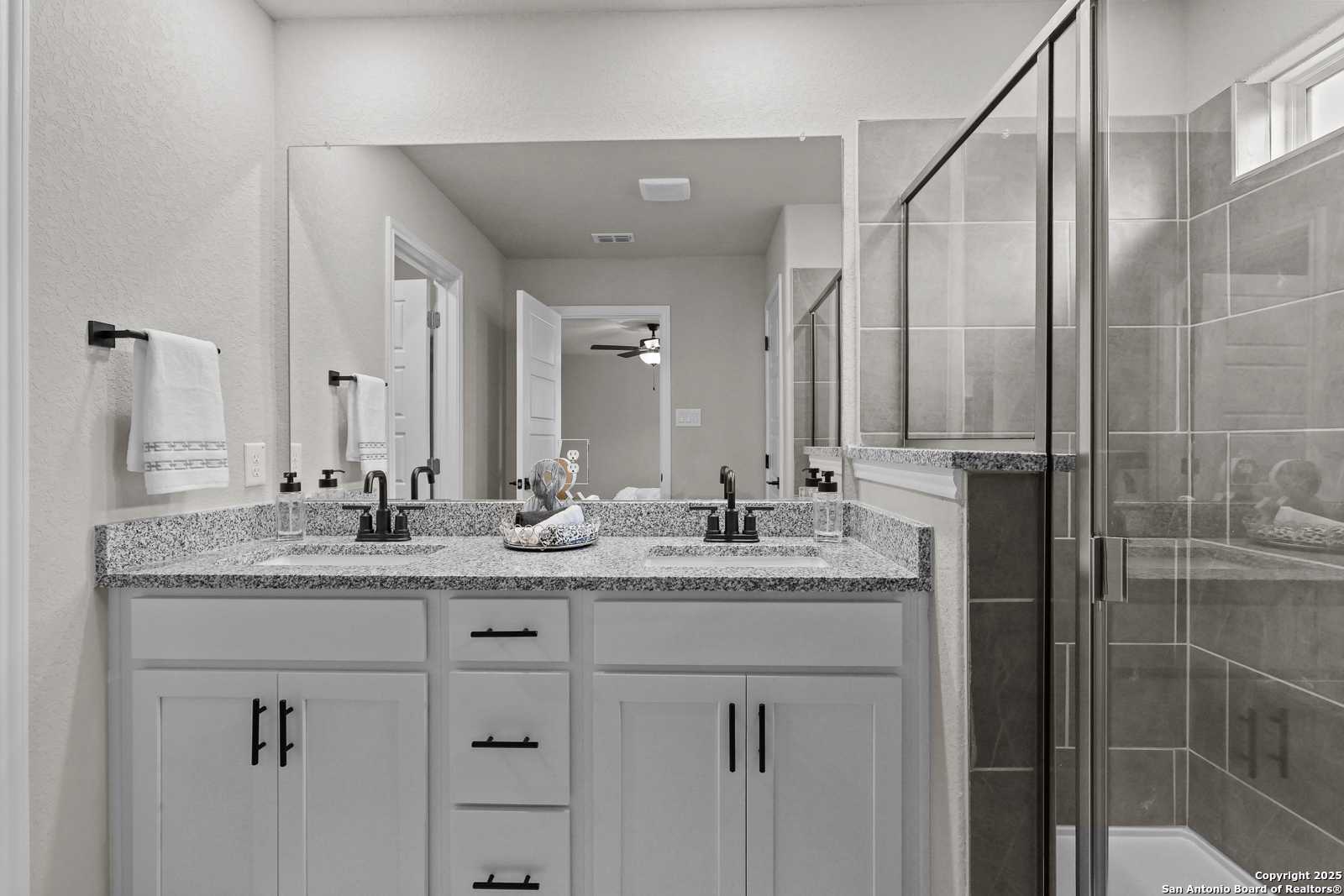 Elegant master bathroom featuring double granite vanity, glass walk-in shower, and white cabinets in Davidson Homes The Charlotte B, San Antonio