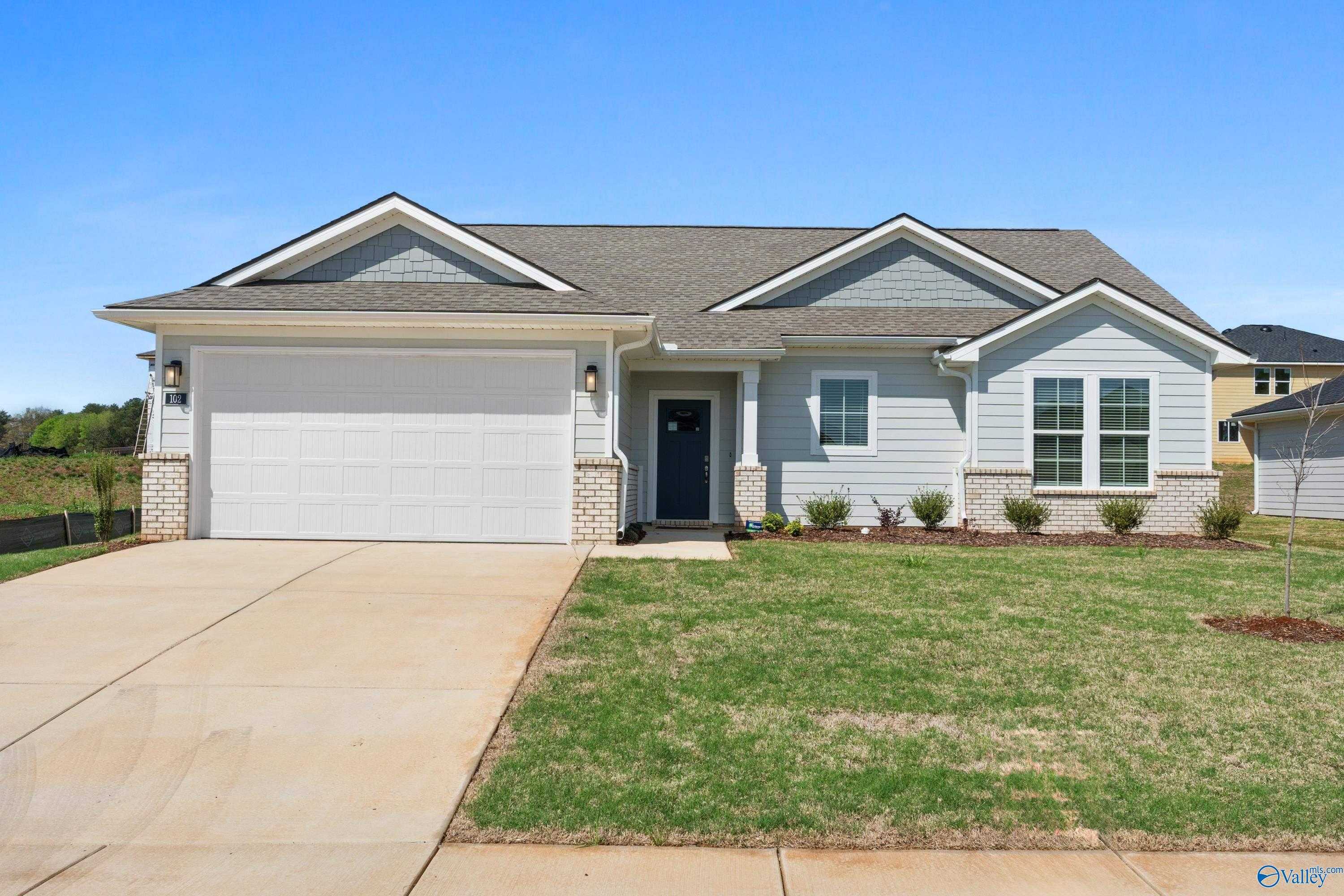 Light blue single-story home with 2-car garage, driveway, and landscaped yard in Evergreen Mill, Madison, Alabama - Evermore Homes The Noble