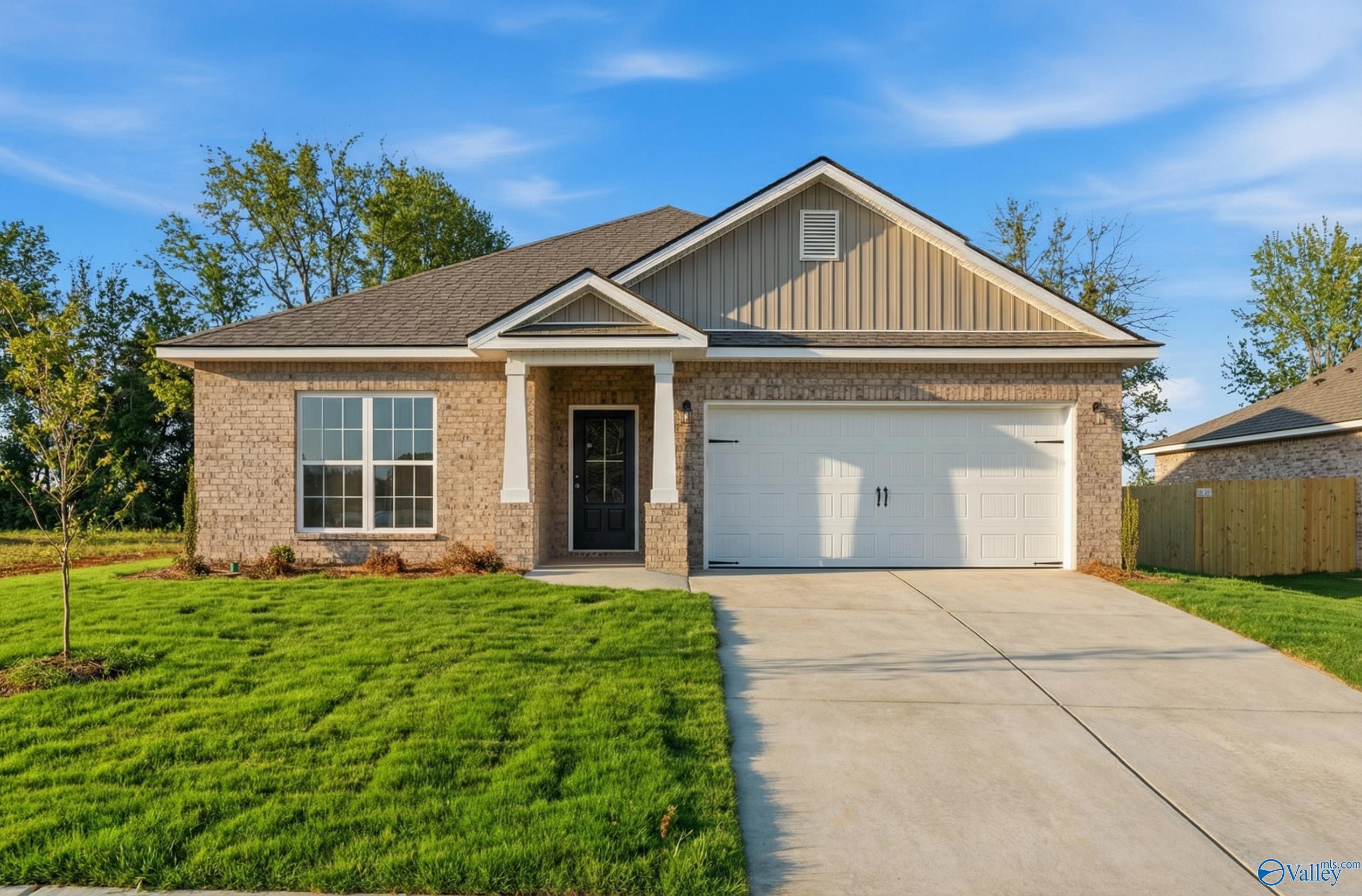 Modern single-story brick home with 2-car garage, covered porch, lush green lawn, and trees in Ivy Hills, Toney, Alabama - Davidson Homes The Daphne C