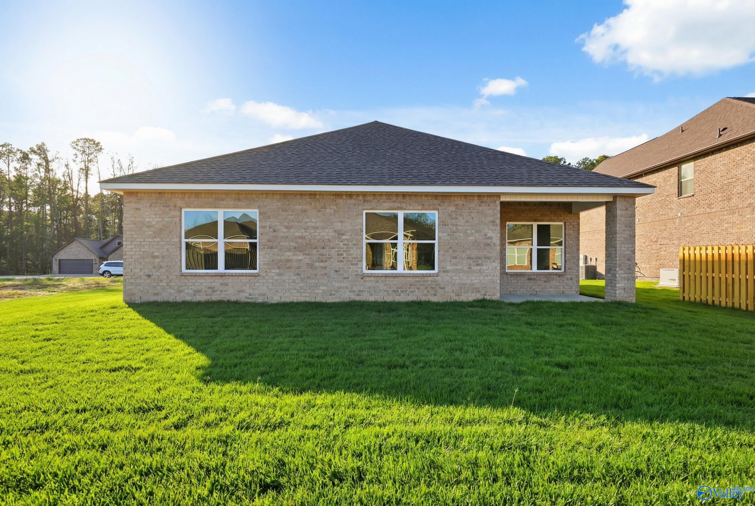 Brick single-story Daphne D home exterior with covered porch, large windows, and lush green lawn in The Highlands, Arab, Alabama