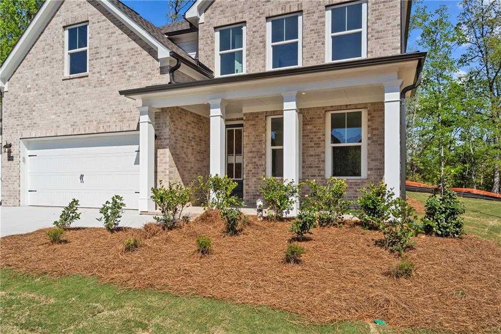 Two-story brick home with columned front porch, one-car garage, and landscaped yard in Melody Lakeside Estates, Buford, Georgia