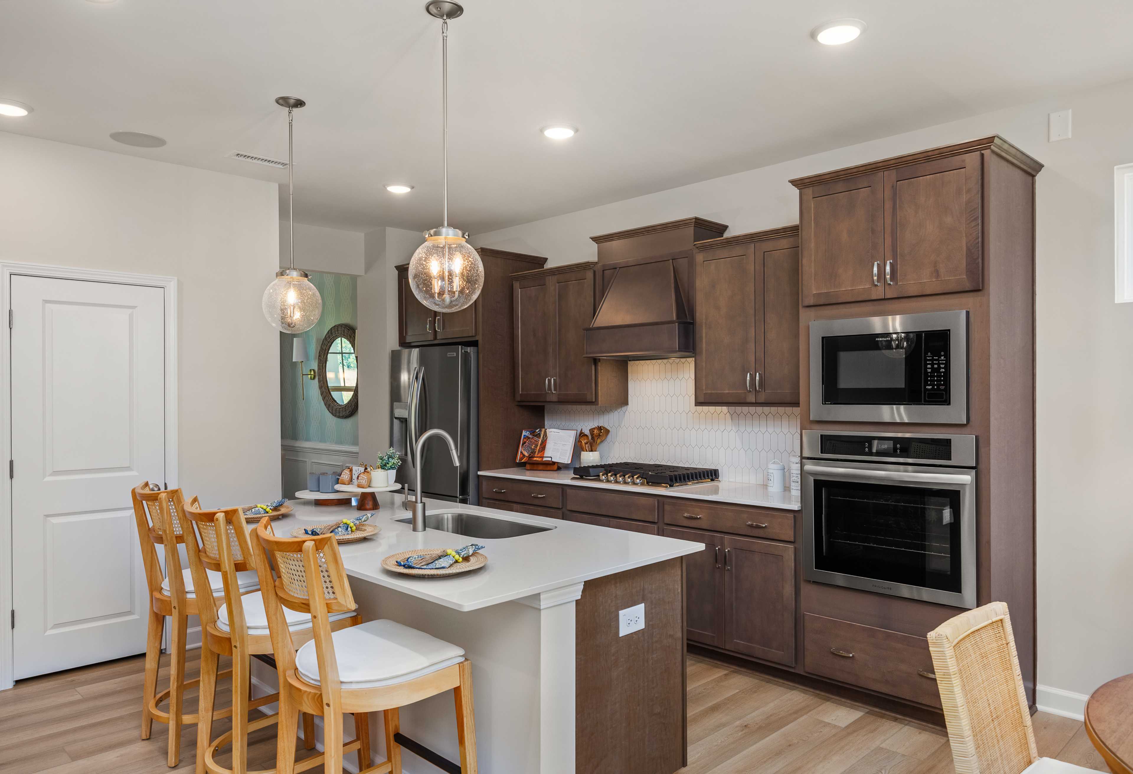 Spacious gourmet kitchen in The Willow G featuring dark wood cabinets, white quartz island, and stainless steel appliances