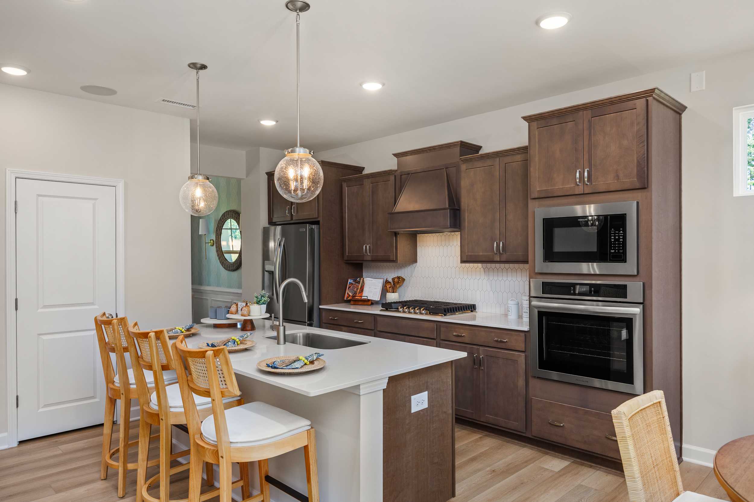 Modern kitchen at Retreat at North Main in Lillington NC with dark wood cabinets, white quartz island, stainless steel appliances, and pendant lights