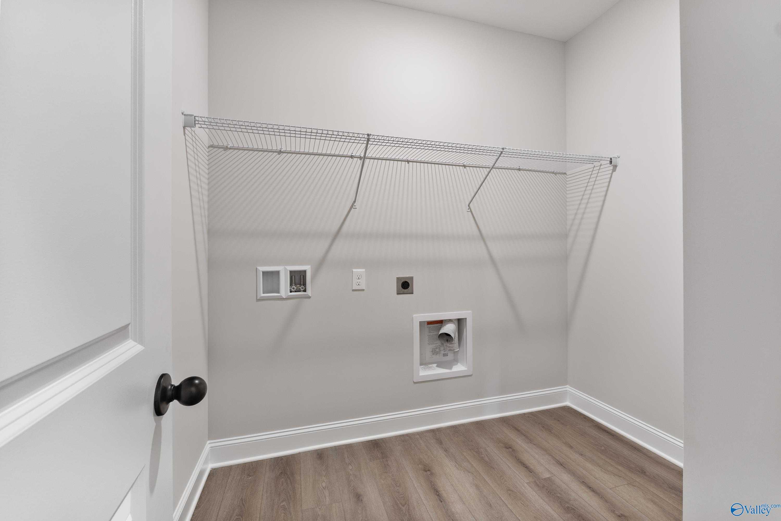 Spacious laundry room with wire shelving, washer-dryer hookups, and utility sink in Davidson Homes The Daphne, Huntsville, AL
