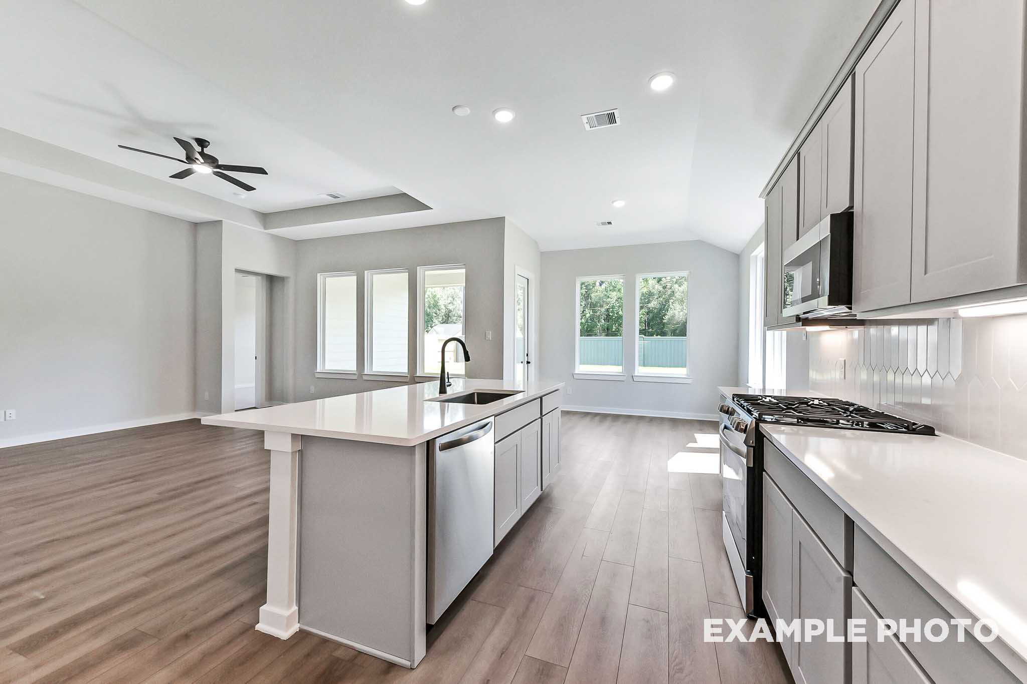 Spacious Sequoia kitchen with large white island, stainless appliances, open layout, wood floors, and natural light from windows