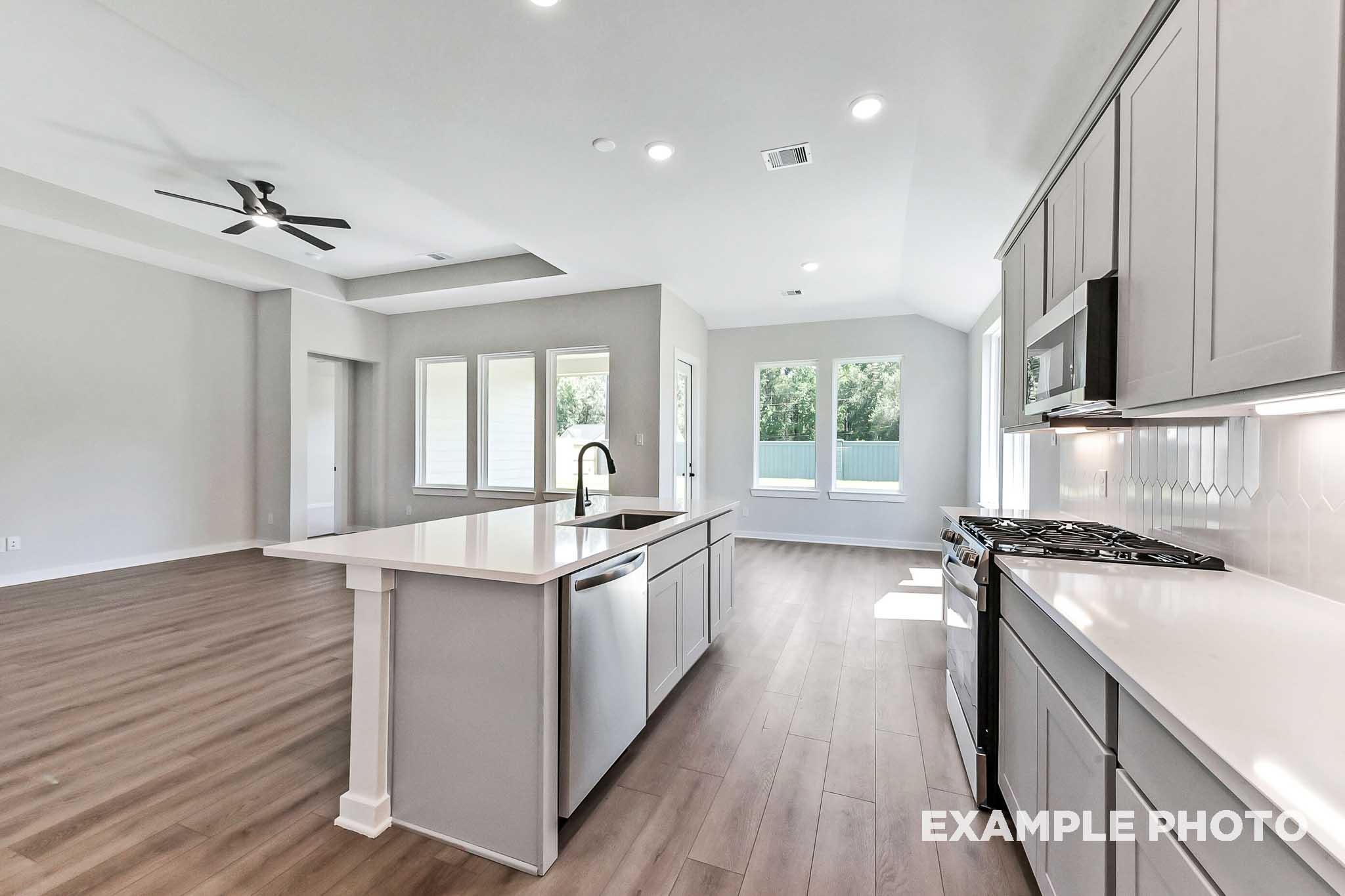 Spacious Sequoia kitchen with large white island, stainless appliances, open layout, wood floors, and natural light from windows