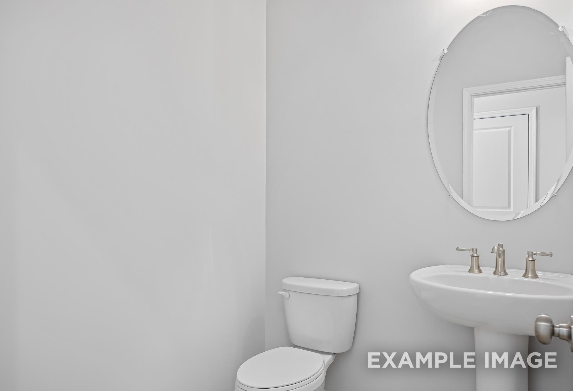 Modern powder room in The Cypress II featuring round mirror, pedestal sink, chrome faucet, and white toilet