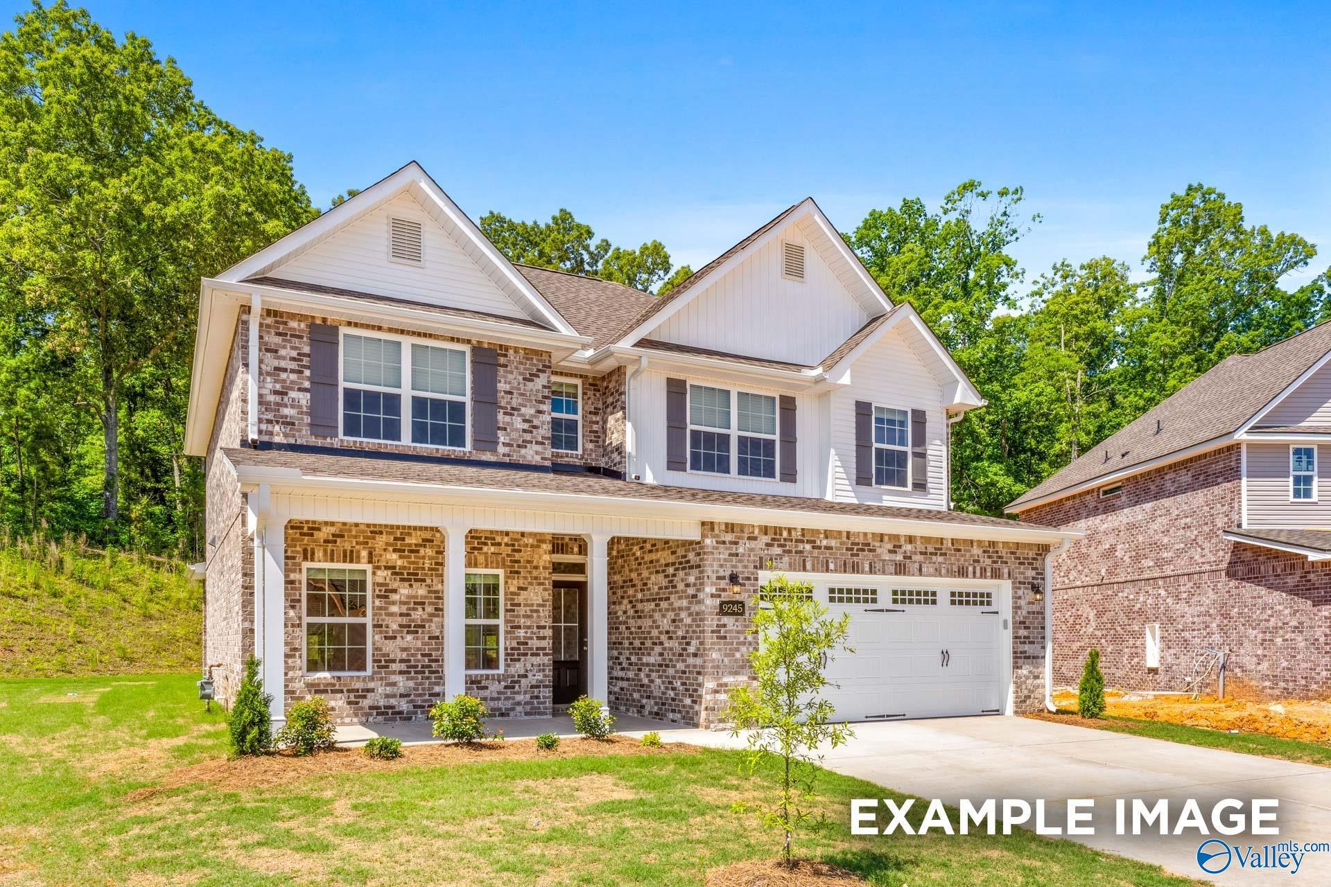Two-story brick and siding home with covered front porch, 2-car garage, and lush landscaping in The Highlands, Arab, Alabama
