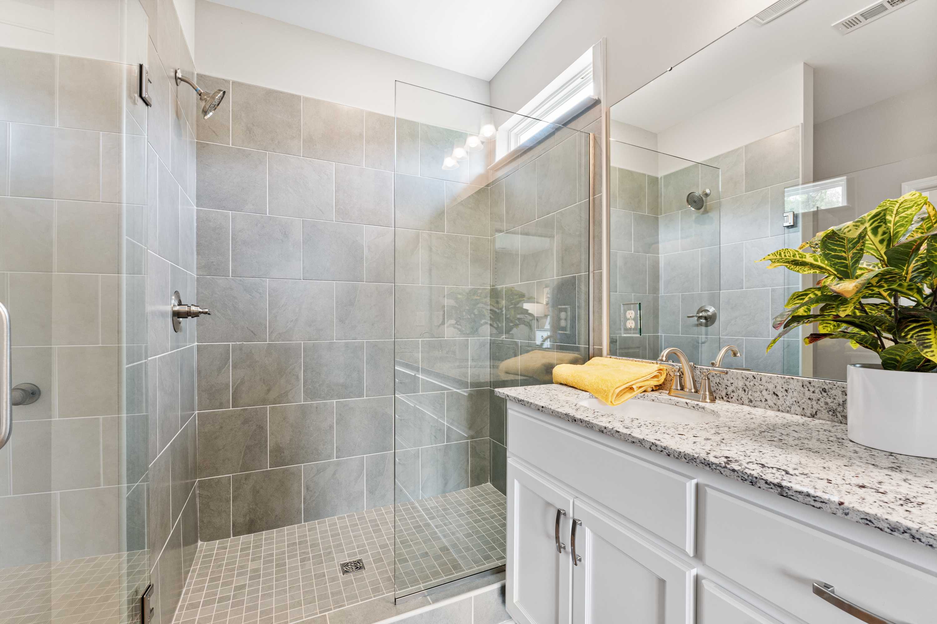Modern bathroom in Forest Glen Hazel Green AL with gray tiled walk-in shower, glass enclosure, and white quartz vanity