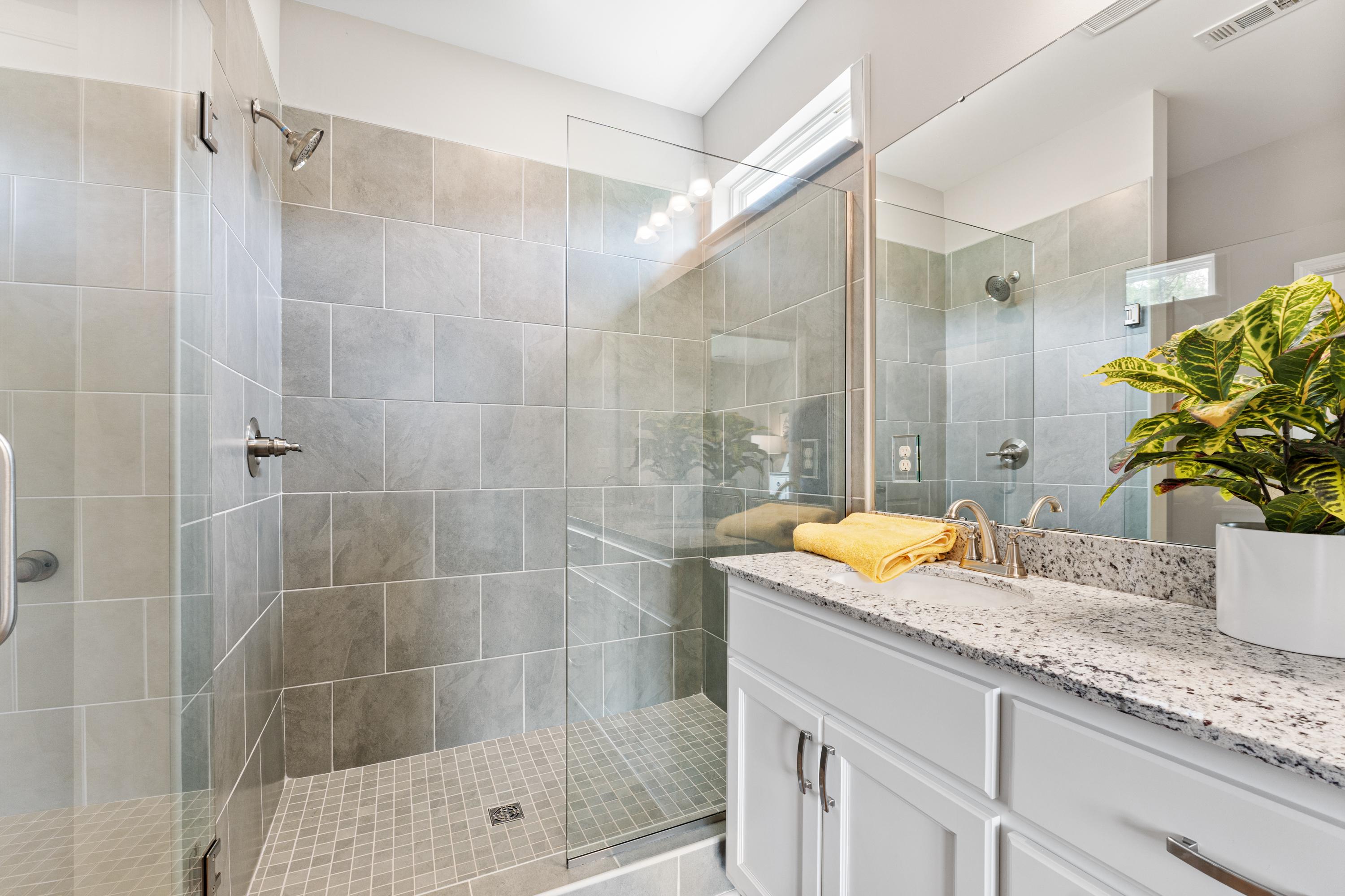 Modern bathroom in Forest Glen Hazel Green AL with gray tiled walk-in shower, glass enclosure, and white quartz vanity