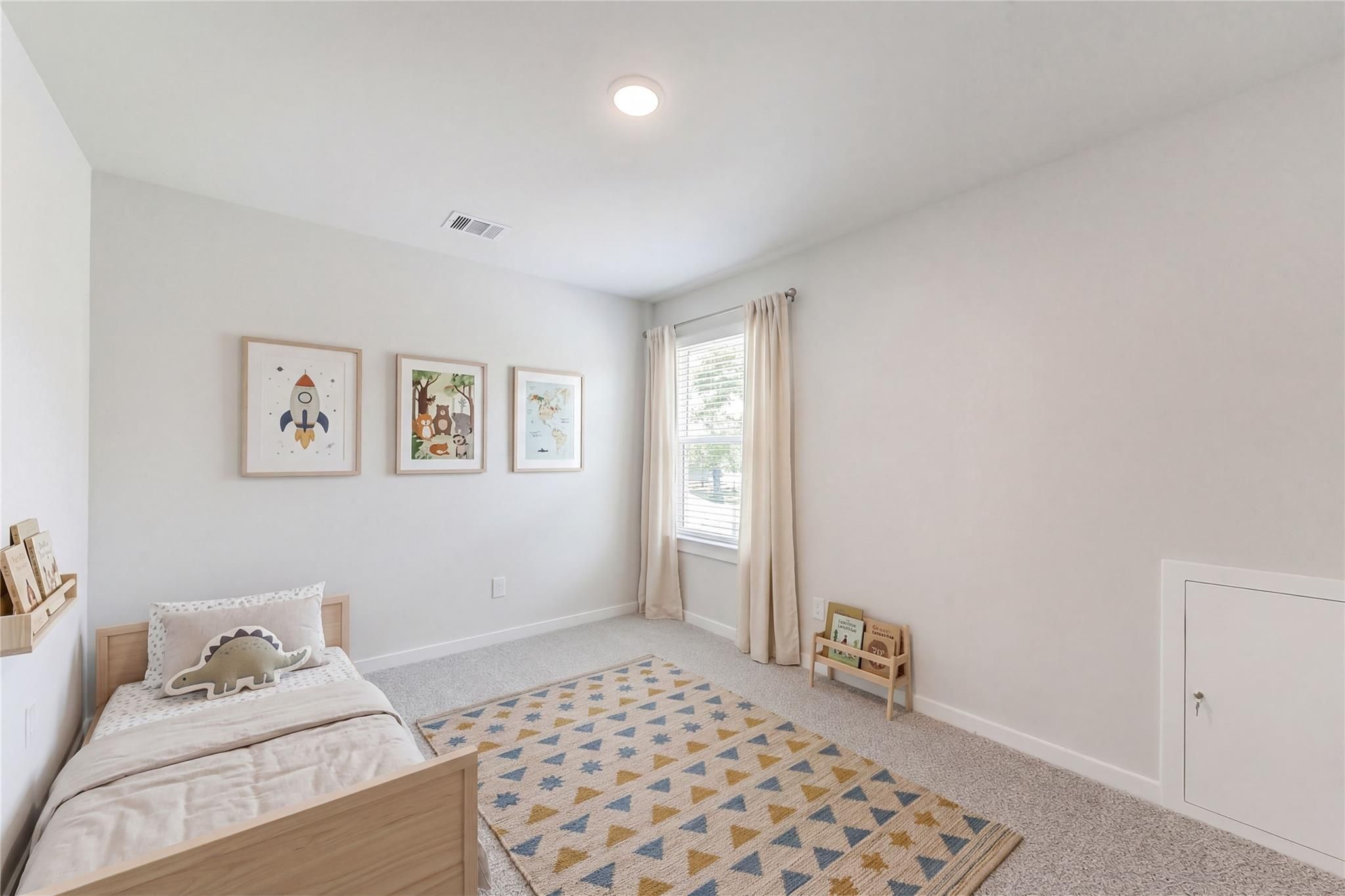 Cozy children's bedroom with twin bed, stuffed elephant, colorful rug, and rocket art in Davidson Homes The Brazos E, Magnolia, Texas