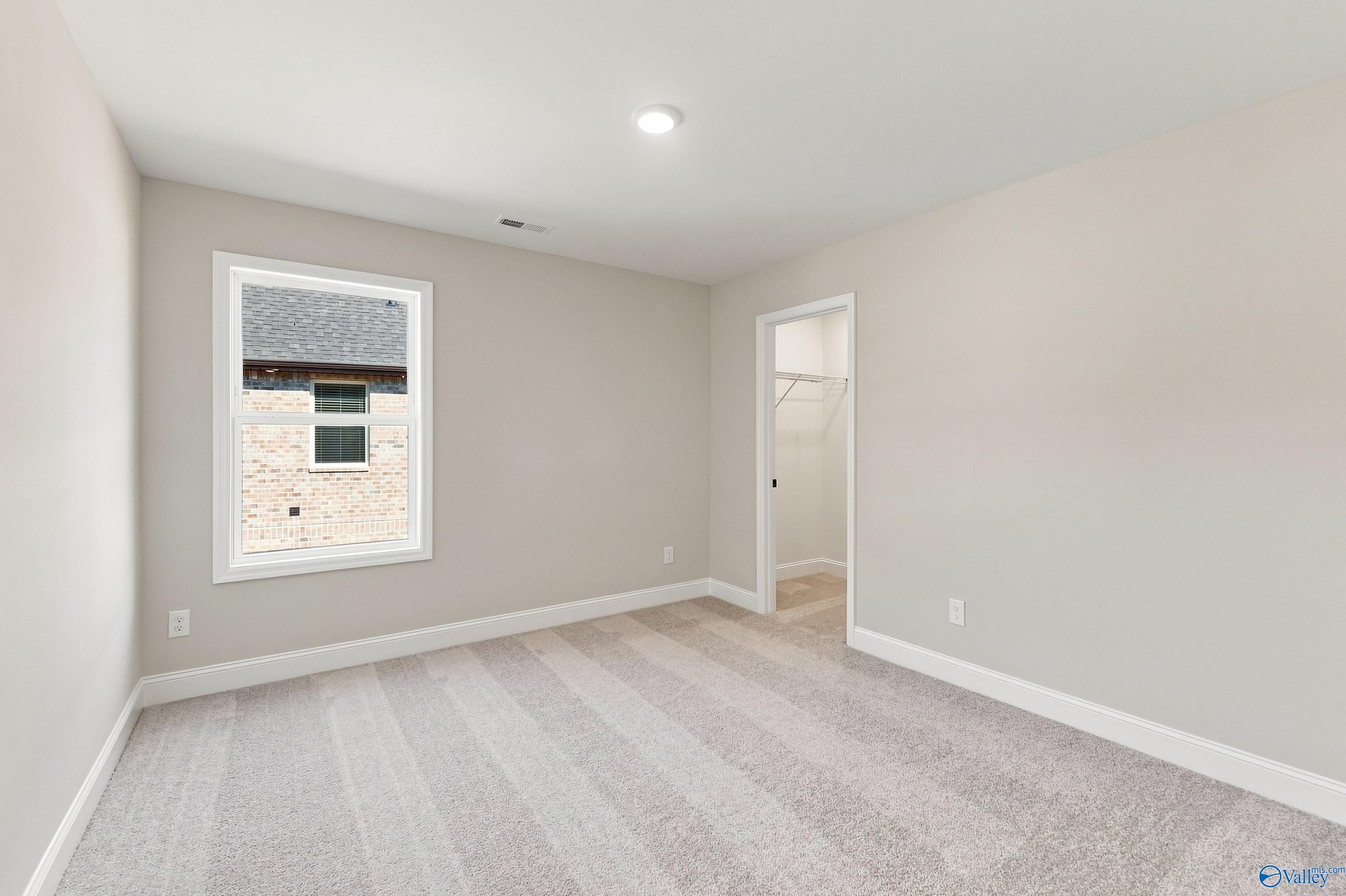 Bright carpeted bedroom with white trim and walk-in closet in Davidson Homes Chelsea B floor plan, New Market, Alabama