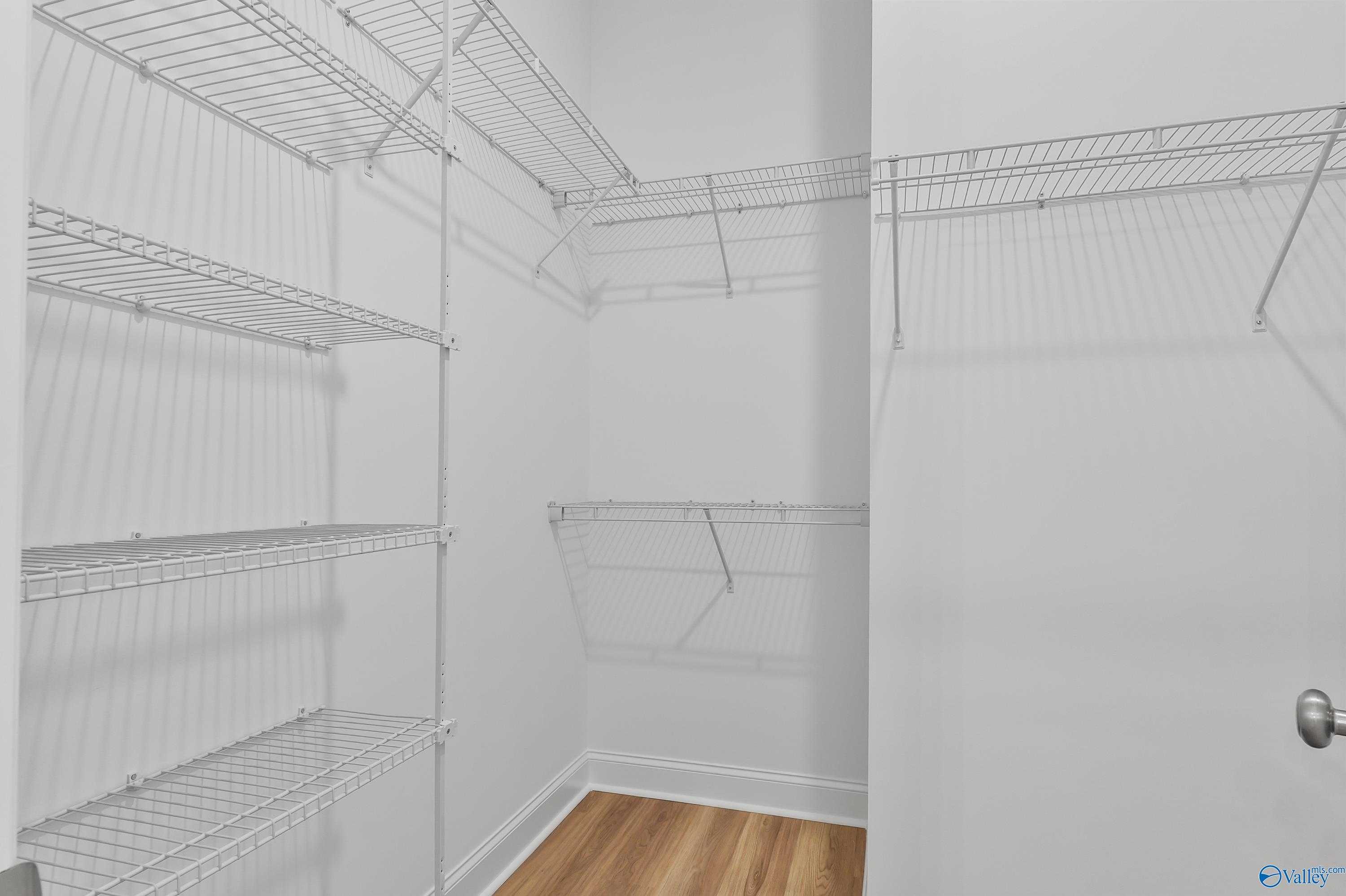 Spacious walk-in closet with wire shelving and hardwood floors in Evermore Homes The Haven, Owens Cross Roads, Alabama