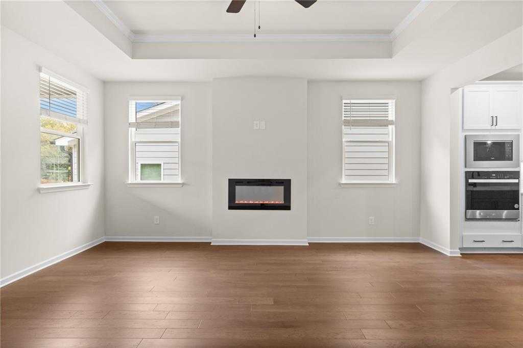 Open-concept living room with modern gas fireplace, hardwood floors, and adjacent kitchen in Davidson Homes The Glenwood C, Loganville, GA