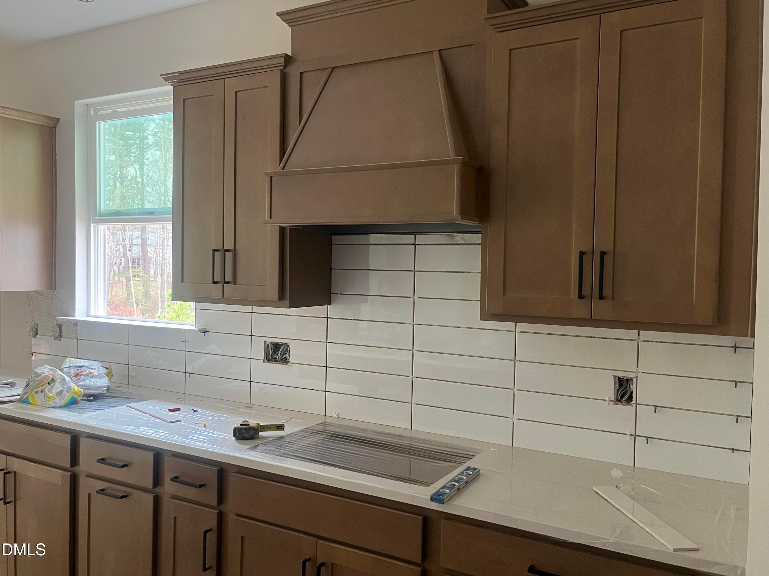 Modern kitchen with brown shaker cabinets, white subway tile backsplash, quartz counters in Davidson Homes The Ashport L, Wake Forest NC