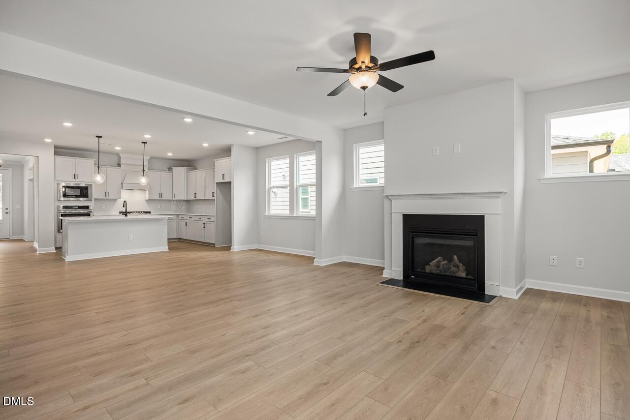 Open-concept living room with gas fireplace and kitchen in The Birch II E floor plan, Sage on North Main, Wake Forest.