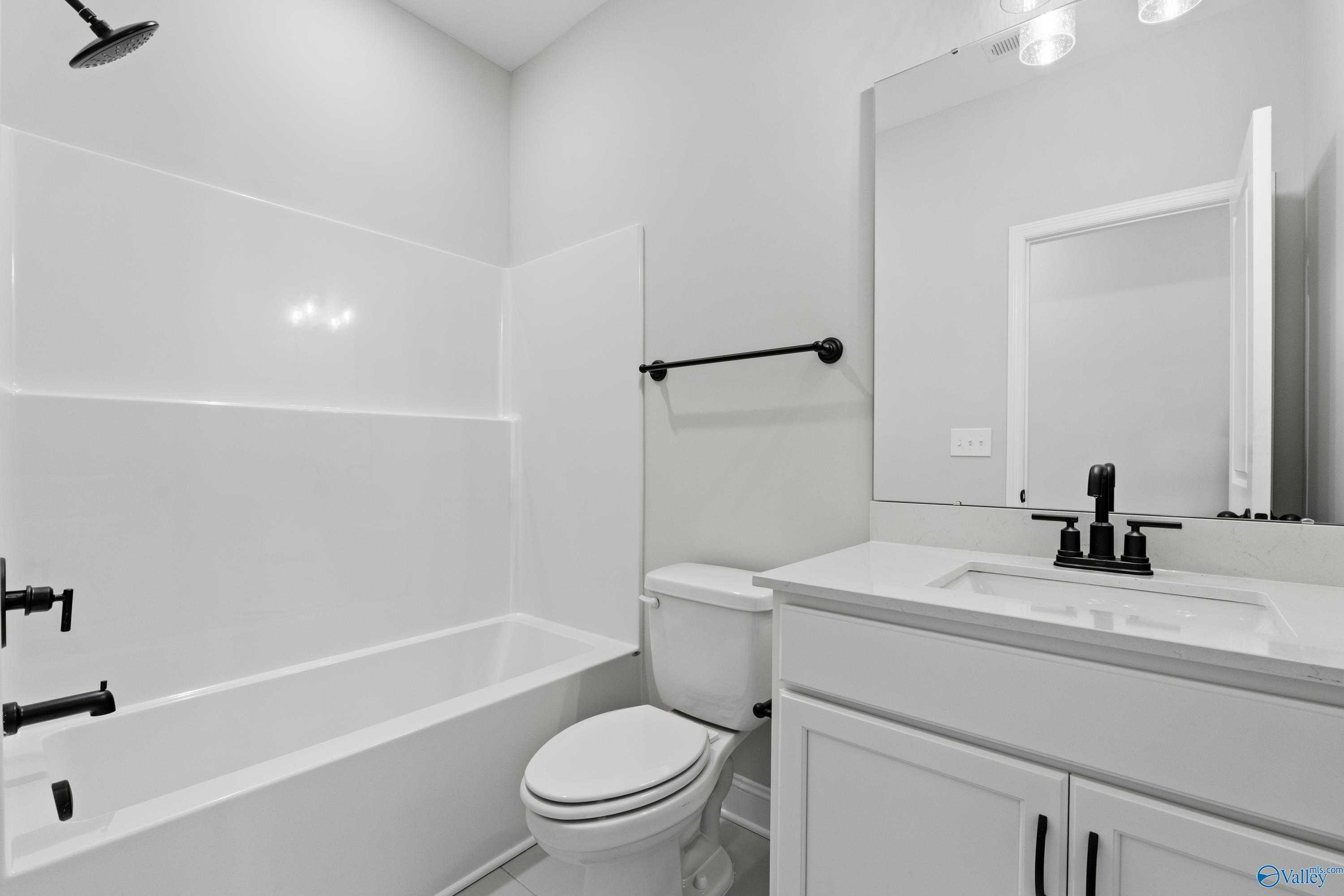 Bright white secondary bathroom with soaking tub, tiled shower, and modern vanity in Davidson Homes The Rockford, Toney, Alabama
