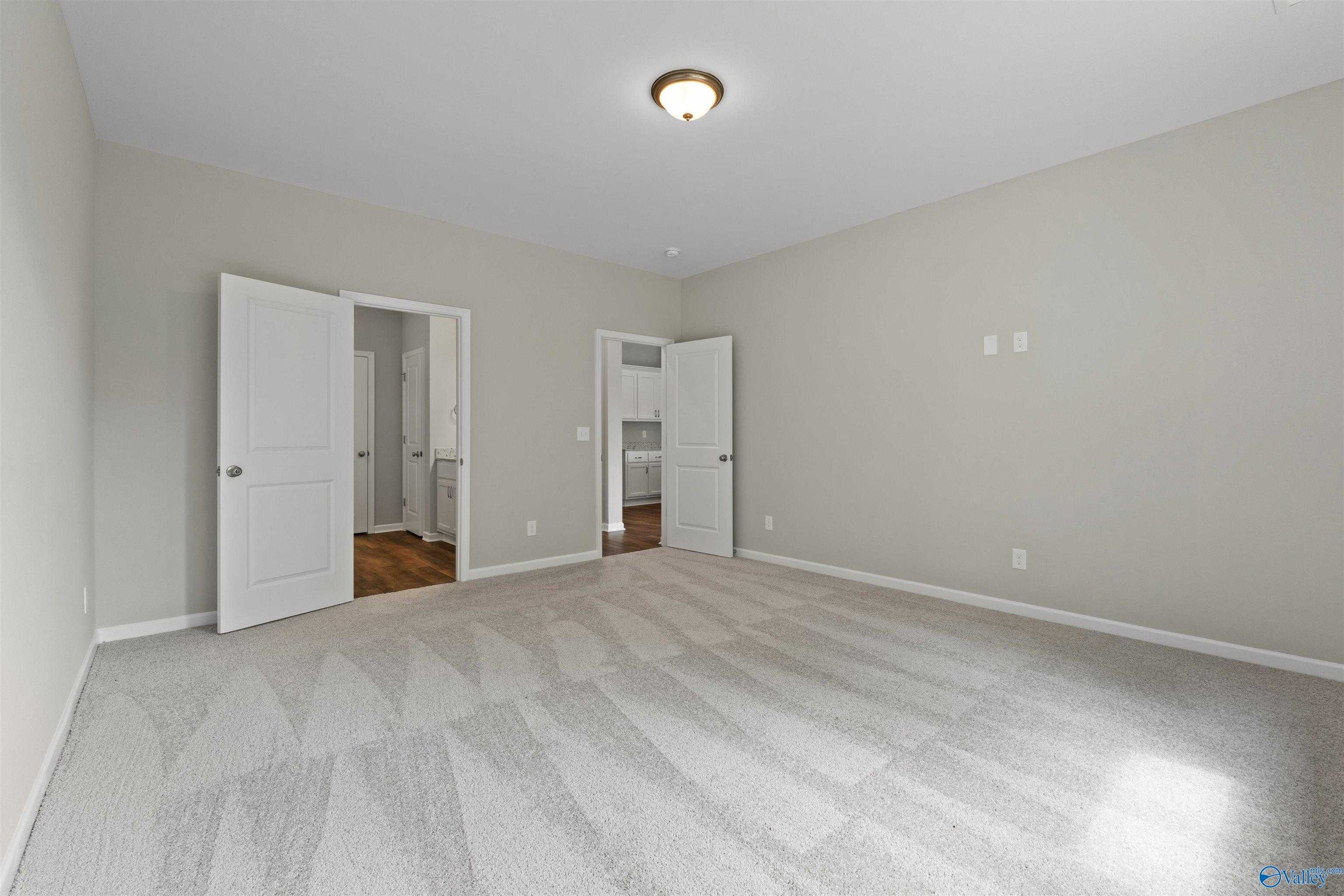 Spacious neutral-toned room with open doors to laundry and kitchen in Davidson Homes The Luna 4-bedroom, Hazel Green, Alabama