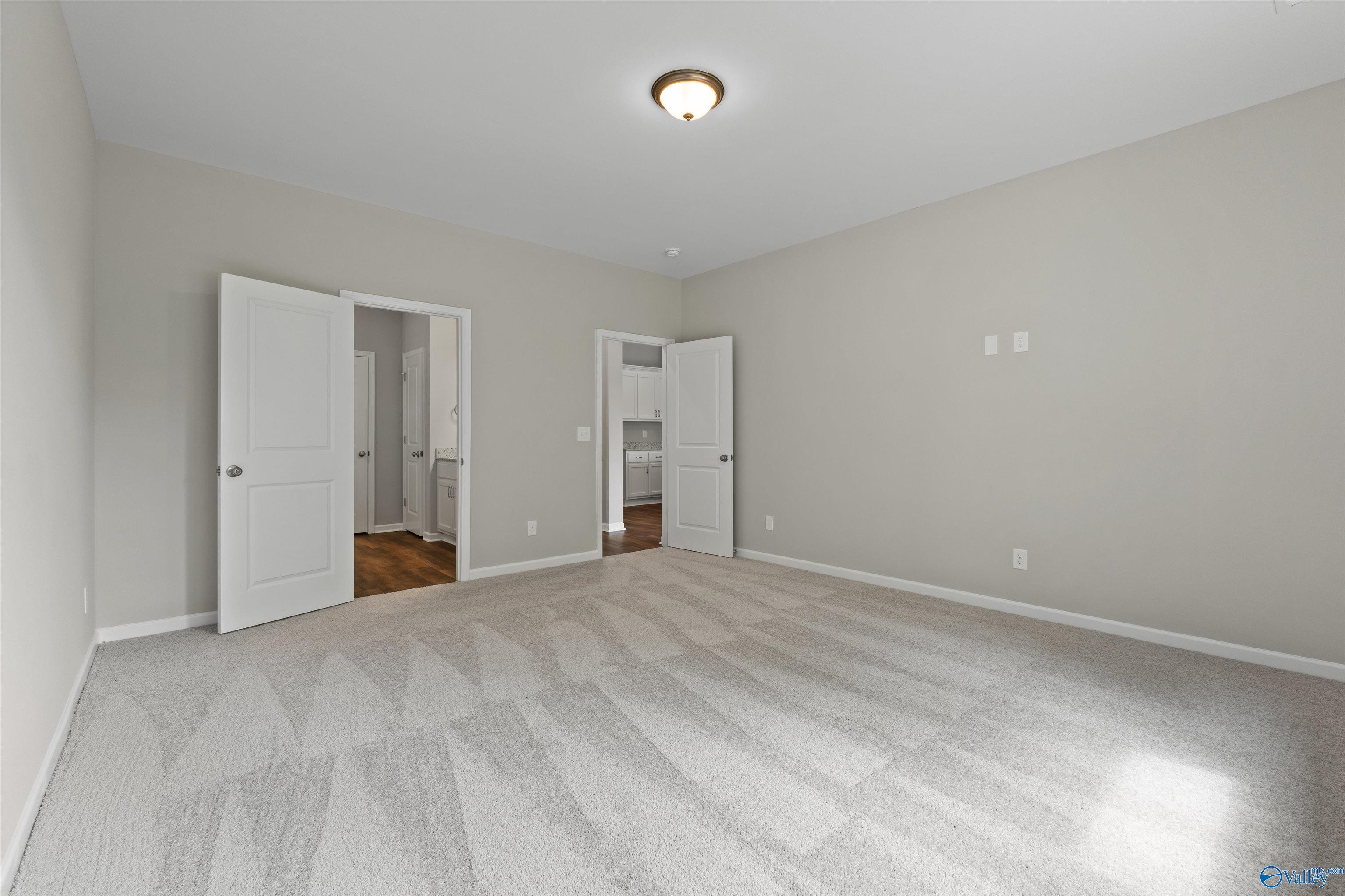 Spacious neutral-toned room with open doors to laundry and kitchen in Davidson Homes The Luna 4-bedroom, Hazel Green, Alabama