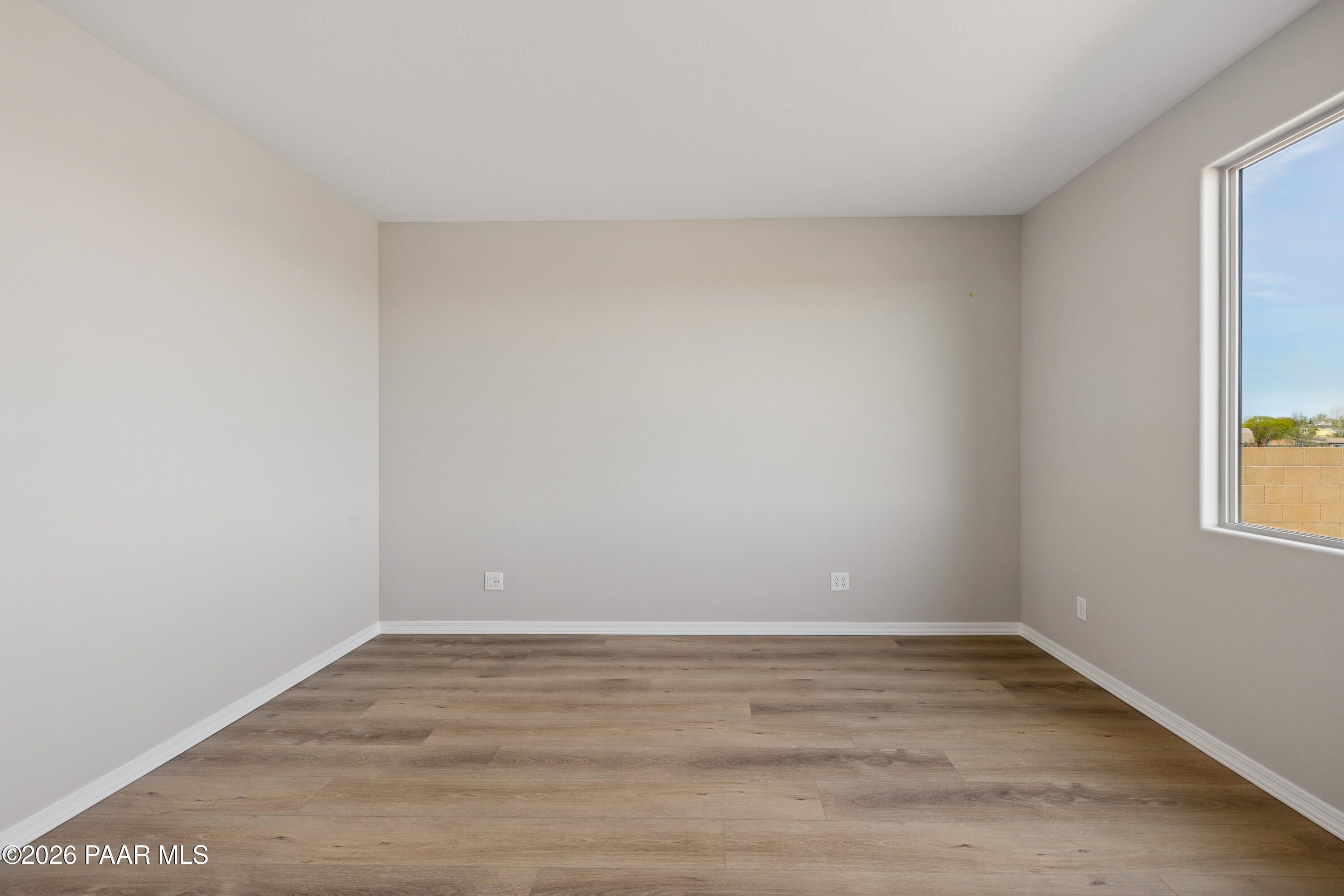 Bright empty bedroom with beige walls, light wood laminate floors, large desert-view window in Davidson Homes The Harmony A, Prescott Valley, AZ