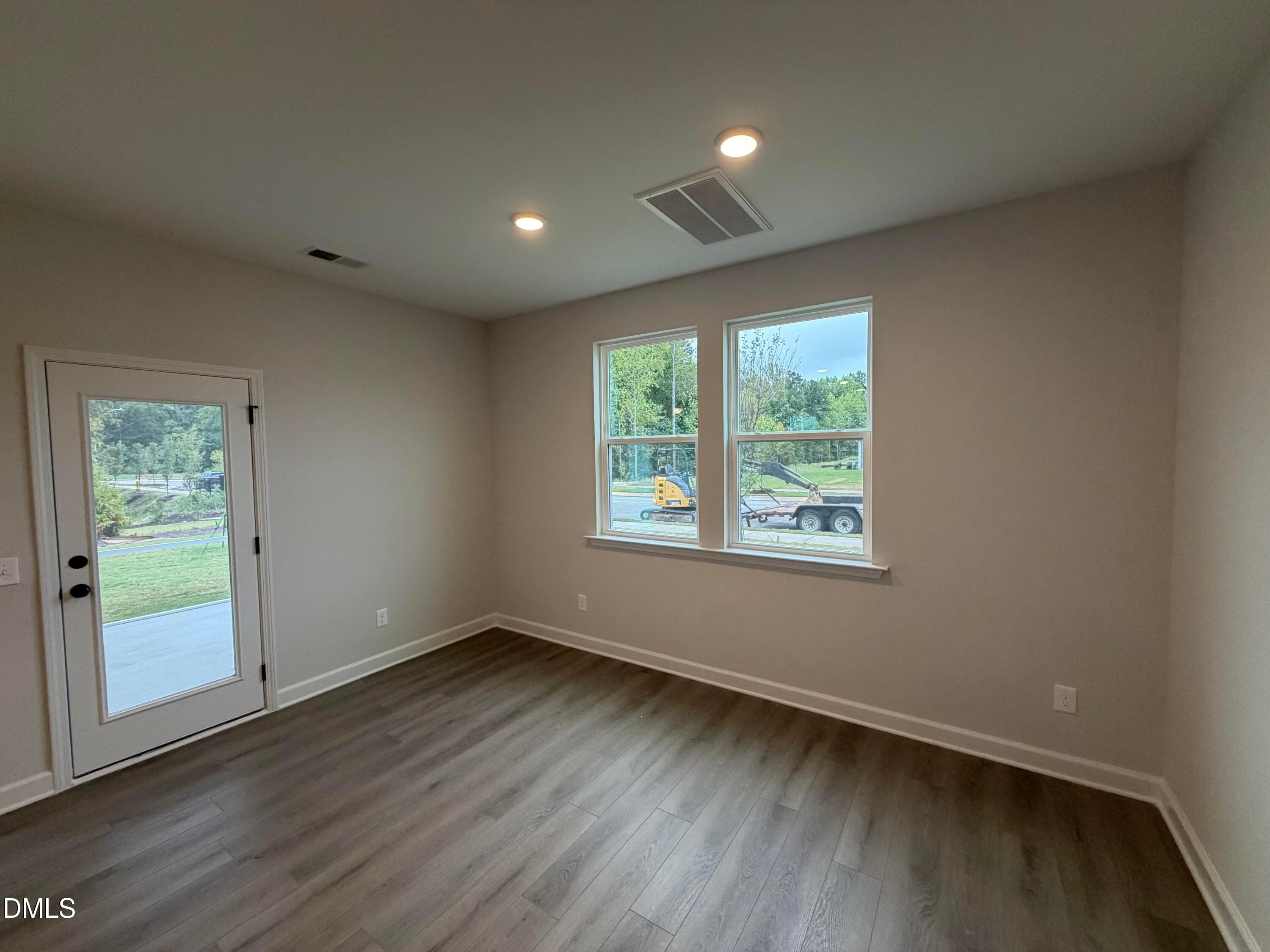 Empty dining room with vinyl plank flooring, double windows, and glass back door in Davidson Homes The Preston C, Wendell Ridge, NC